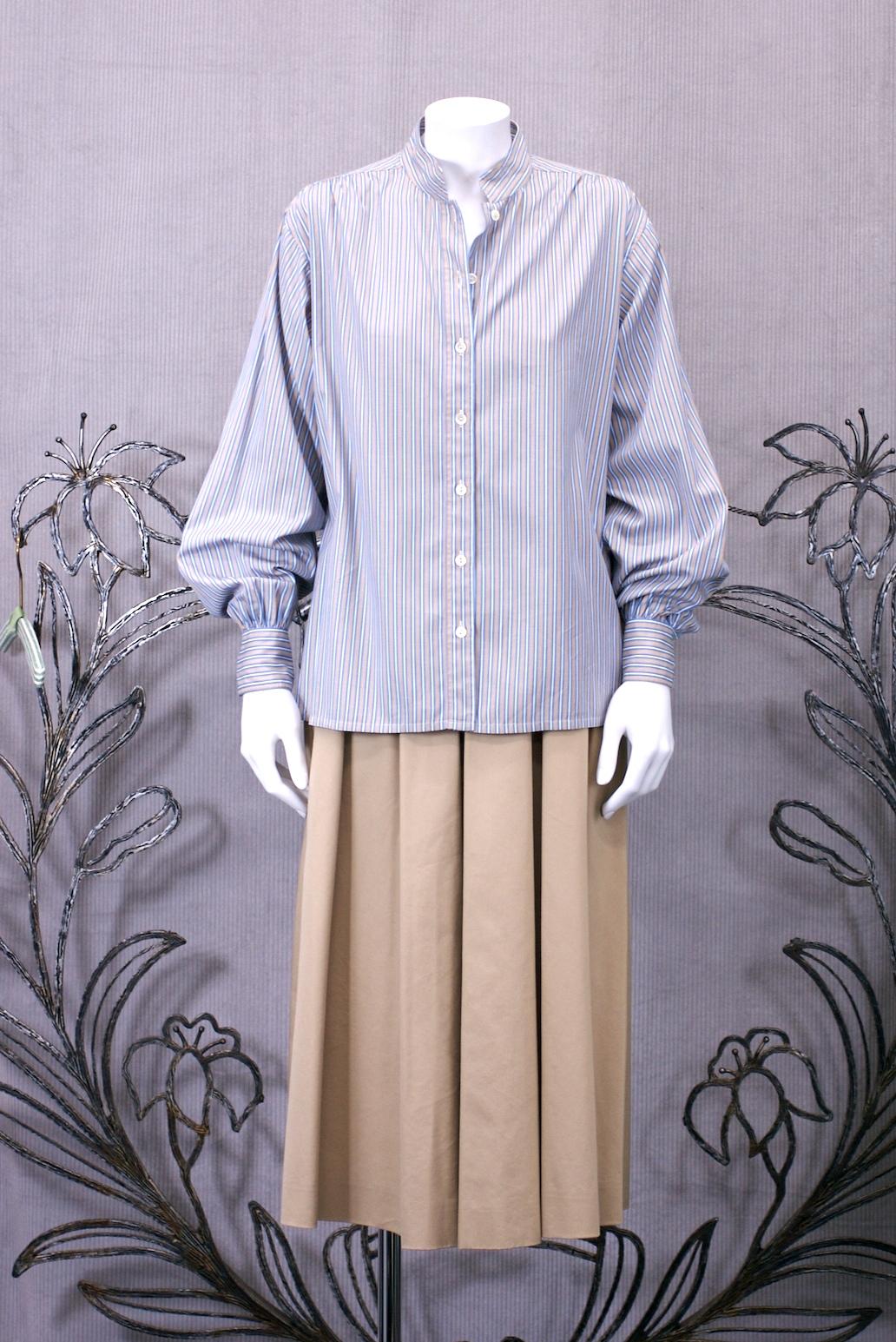 YSL Rive Gauche cotton blouse with band collar and button front entry. Cotton shirting of blue, beige and white stripes. Typical YSL styling of a classic form reinterpreted through a chic French lens. Unworn old stock. 
Nice full sleeves on a