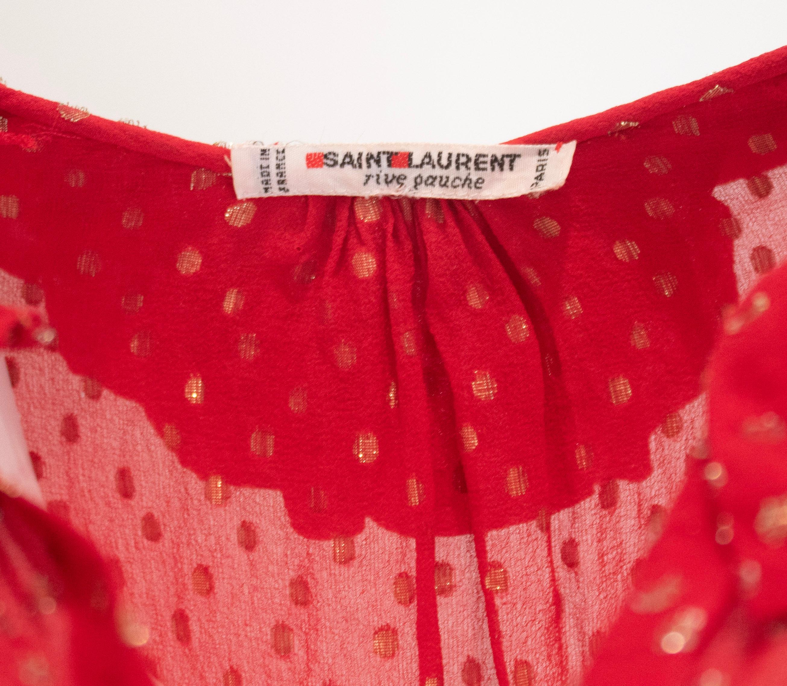 Eleva tu vestuario con esta blusa Vintage Yves Saint Laurent confeccionada en lujosa seda suiza roja punteada. Su tejido vaporoso y su delicado cuello de volante añaden una textura y una elegancia refinadas, convirtiéndolo en una pieza versátil