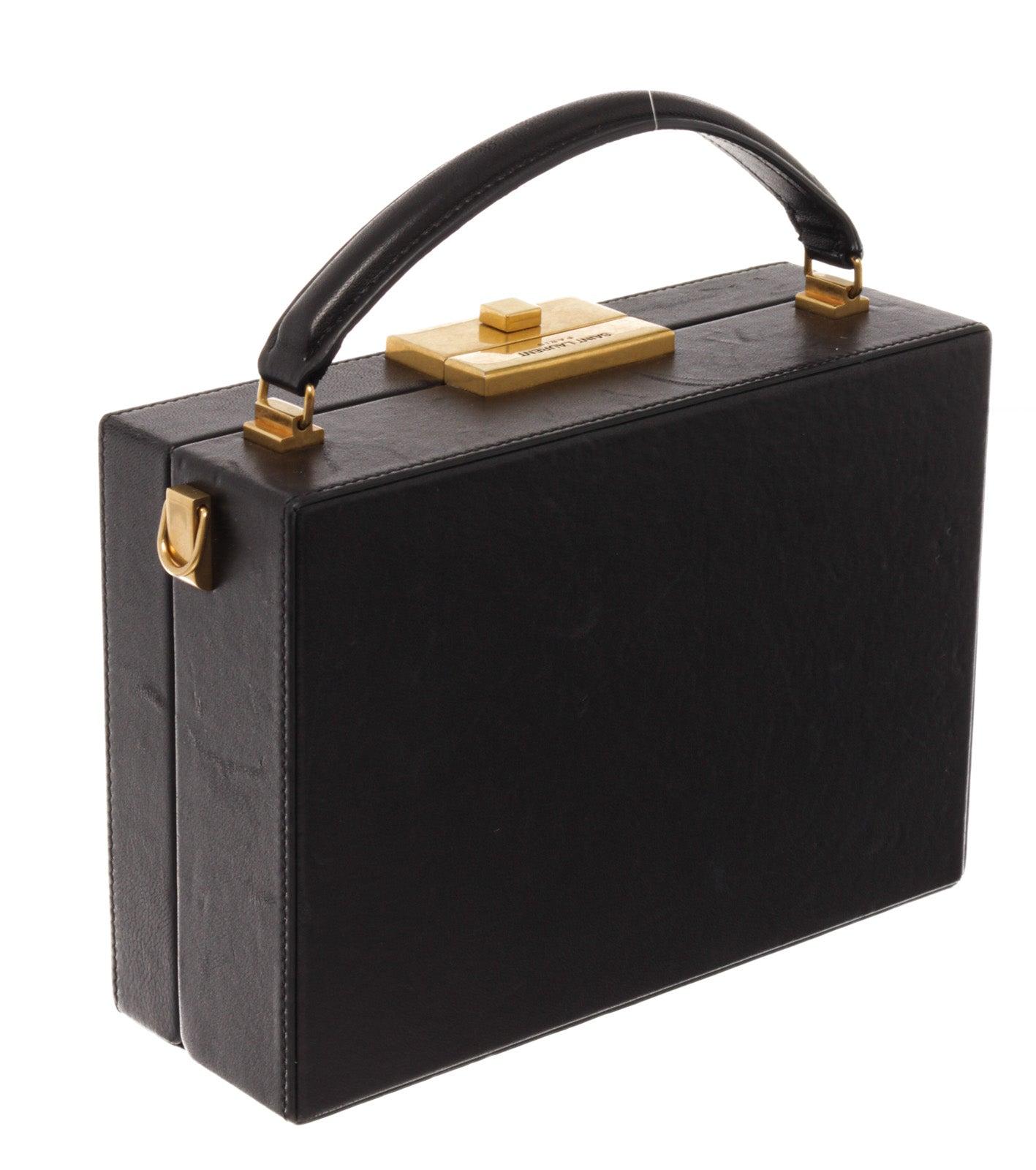 Saint Lauren YSL Black Lather Nan Box Bag ist eine kastenförmige Umhängetasche, oben mit einem flexiblen Ledergriff zum Tragen in der Hand mit goldfarbener Hardware, es gibt auch ein Hauptfach mit 1 Kartenschlitz innen. und der Boden verfügt über 4