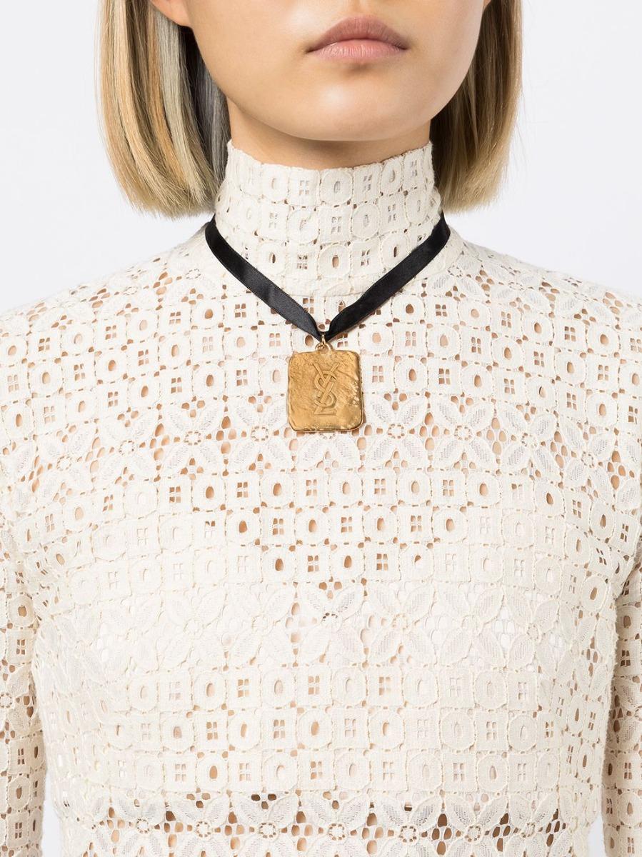 Elevate any outfit with this vintage YSL pendant by Robert Goossens. Tie around your neck with a black satin cord, this unique piece features a hammered gold-toned square pendant embossed with the iconic YSL logo. Wear against a bare décolletage,