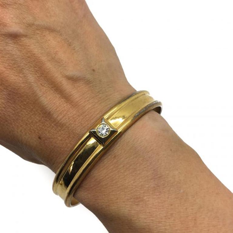 A very stylish and good quality Vintage YSL bangle dating to the late 70s, early 80s. The bangle is designed in a simple band design with a ridged edge and single crystal rhinestone detailing to the front. There is a small amount of age appropriate