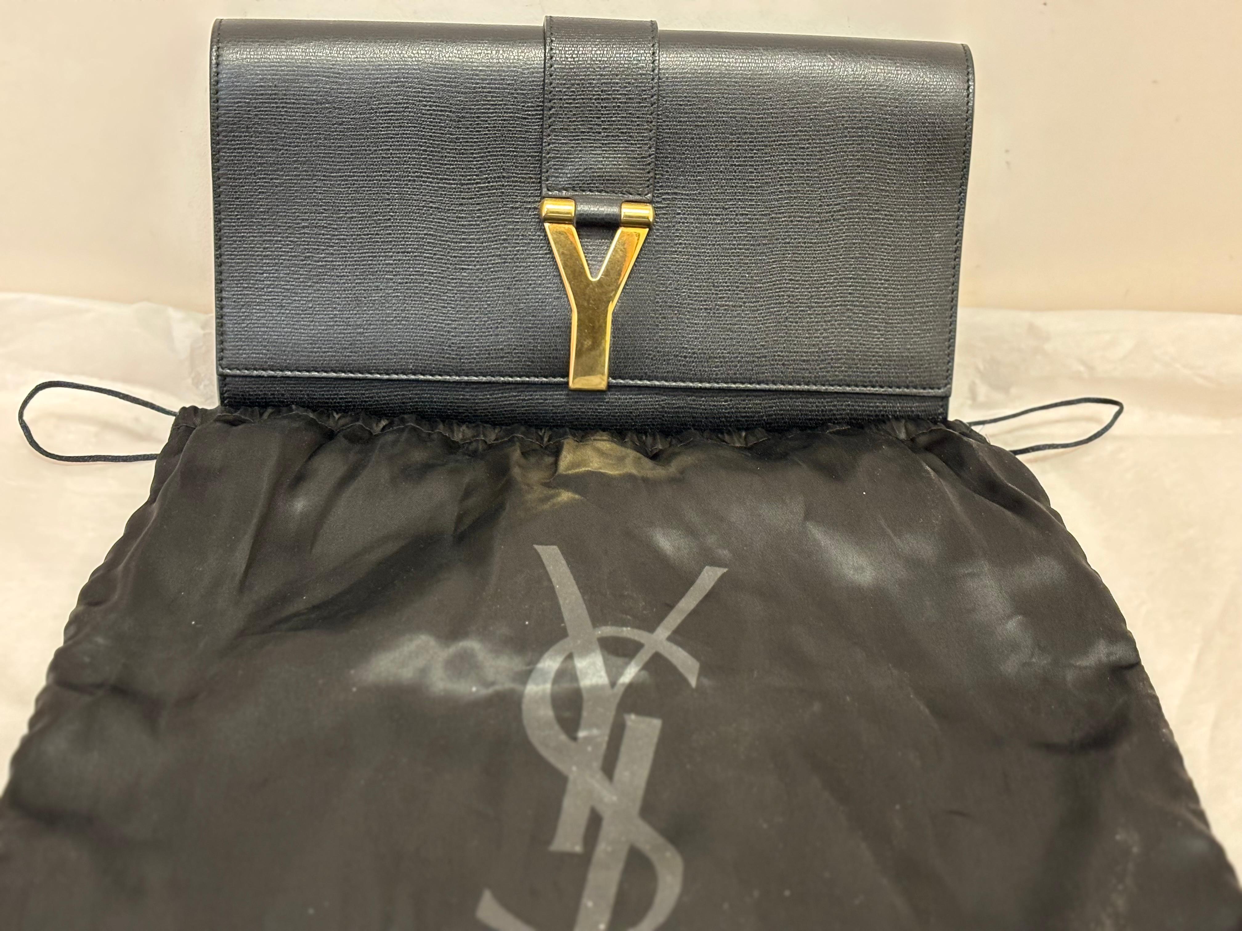 Typical YSL bag, simple lines and muted sophistication. This YSL Y Ligne clutch was designed by Tom Ford and is made of textured leather.
This clutch has a front magnetic flap, featuring a gold-tone Y, the interior is satin lined with a patch
