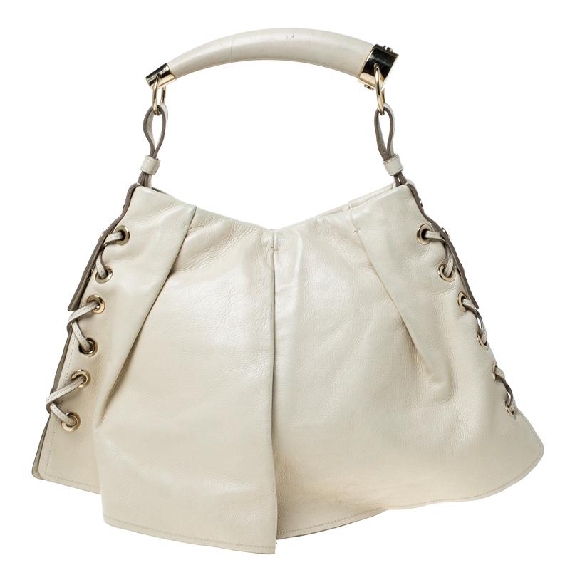 Ti piacerà avere questa borsa a tracolla Saint Laurent Paris Rive Gauche Mombasa. Realizzata in pelle beige con dettagli di cuciture a frusta sui lati, questa bellezza è sostenuta da un manico a forma di corno. Chiuso da un bottone magnetico a