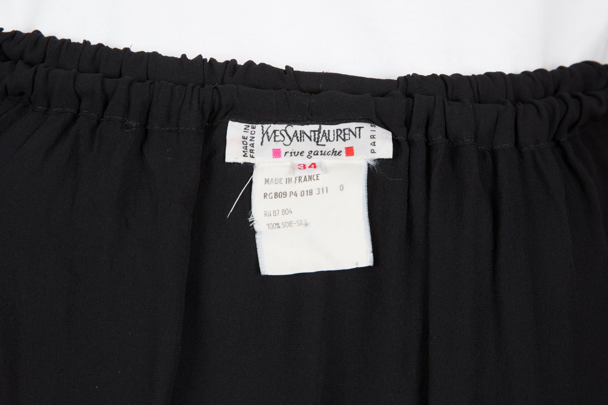 YSL Yves Saint Laurent black evening silk skirt featuring a high-waisted skirt, asymmetrical semi-sheer draping, elastic waistband. 
Composition: 100% Silk 
Estimated size 34fr/US2 /UK6
In good vintage condition. Made in France.
Circa 1990s
We