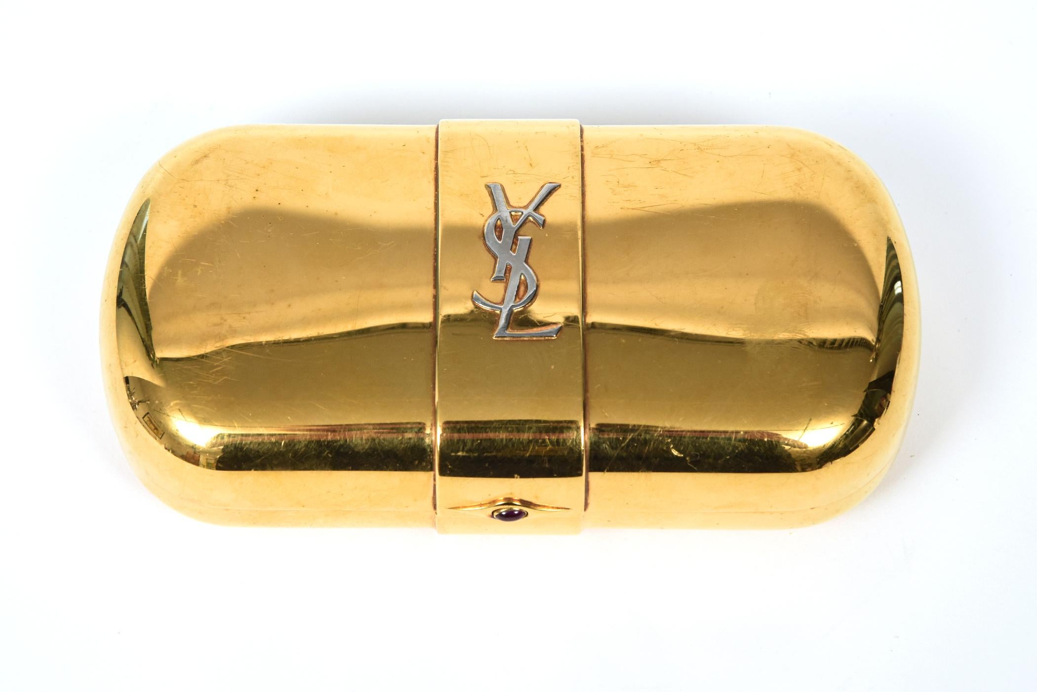 Vintage gold plated Yves Saint Laurent clutch is perfect for an evening out on the town.  From the 1980s, it features a gold metal exterior with a silver YSL logo in the center.  The inside is a burgundy satin moire interior with a small pocket. 