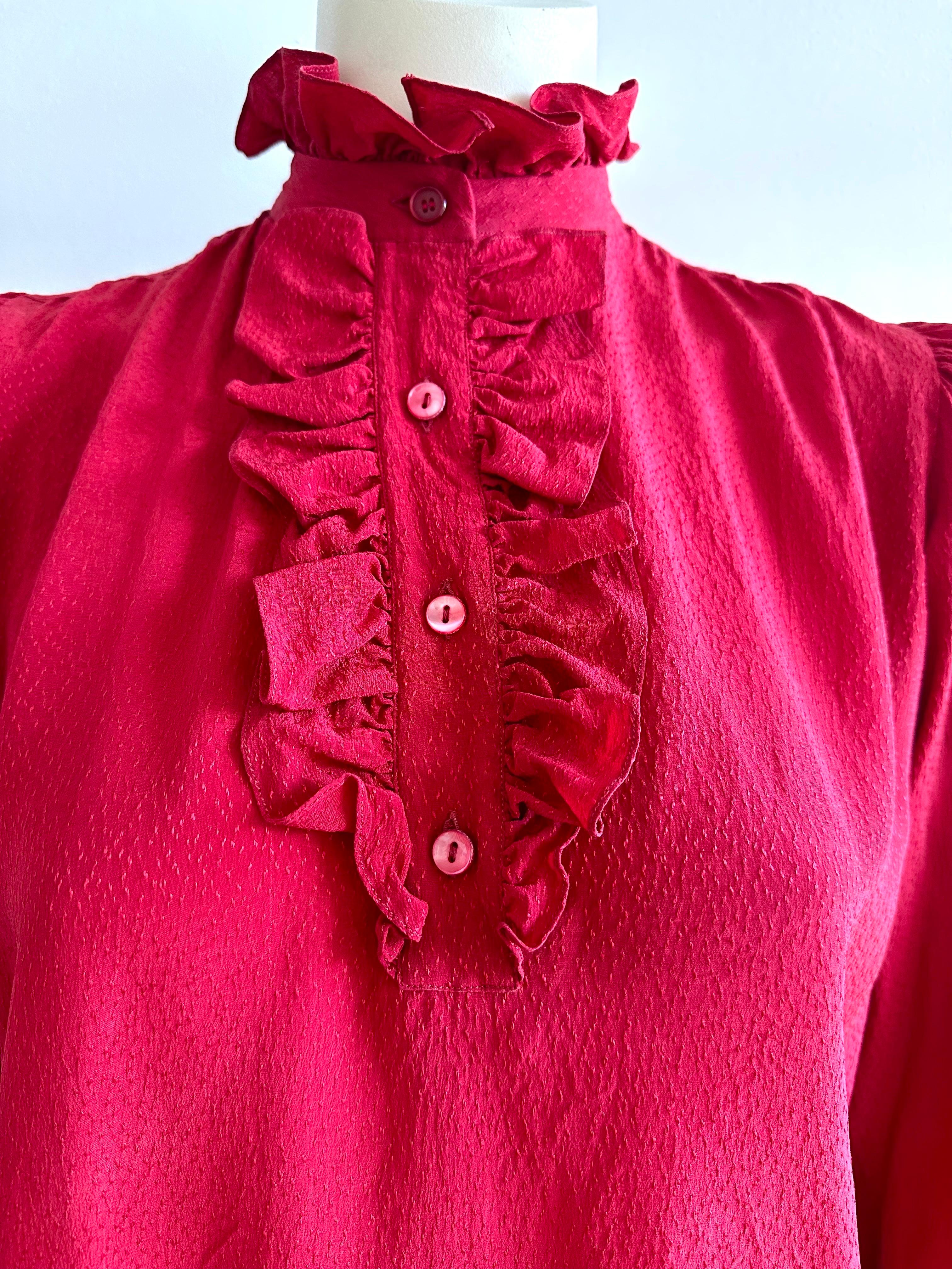 Blouse en soie rouge YSL avec un petit col à volants et une bavette volantée et boutonnée sur le devant.
Manches longues avec poignets volantés et boutonnés.
La taille indiquée est 38 FR, se référer aux mesures
D'une épaule à l'autre 37cm
Largeur de