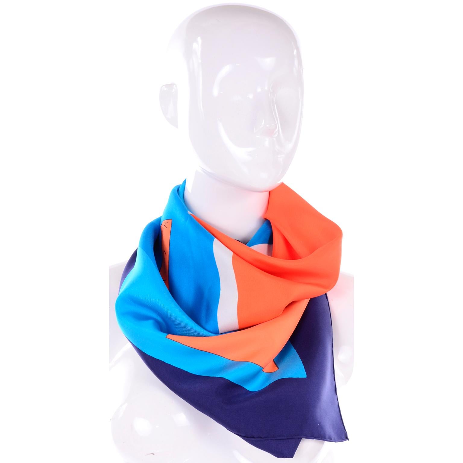 This is a colorful vintage silk scarf designed by Yves Saint Laurent in the late 1970's or early 1980's.  The geometric print is in shades of blue, orange and white. Yves Saint Laurent's signature is found in a rectangle on the bottom center and the