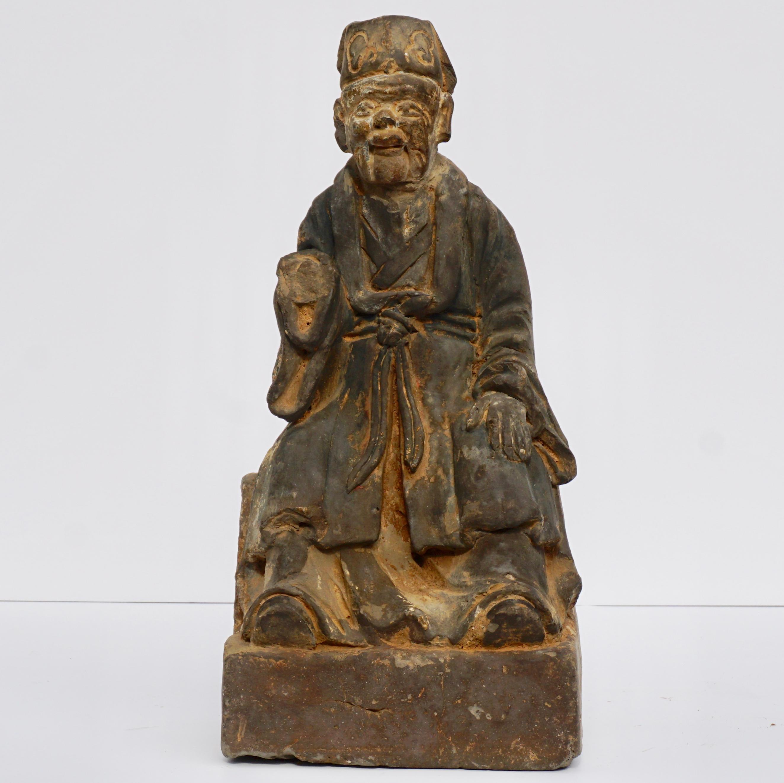 An ancient Chinese carved and painted grey stone sculpture of a dignitary, Laohan, Deity, Emperor or king from the 12th-14th century. Yuan -Ming Dynasty. A seated elderly man robes with a dignitary hat. The figure appears Taoist to Early Buddhist.