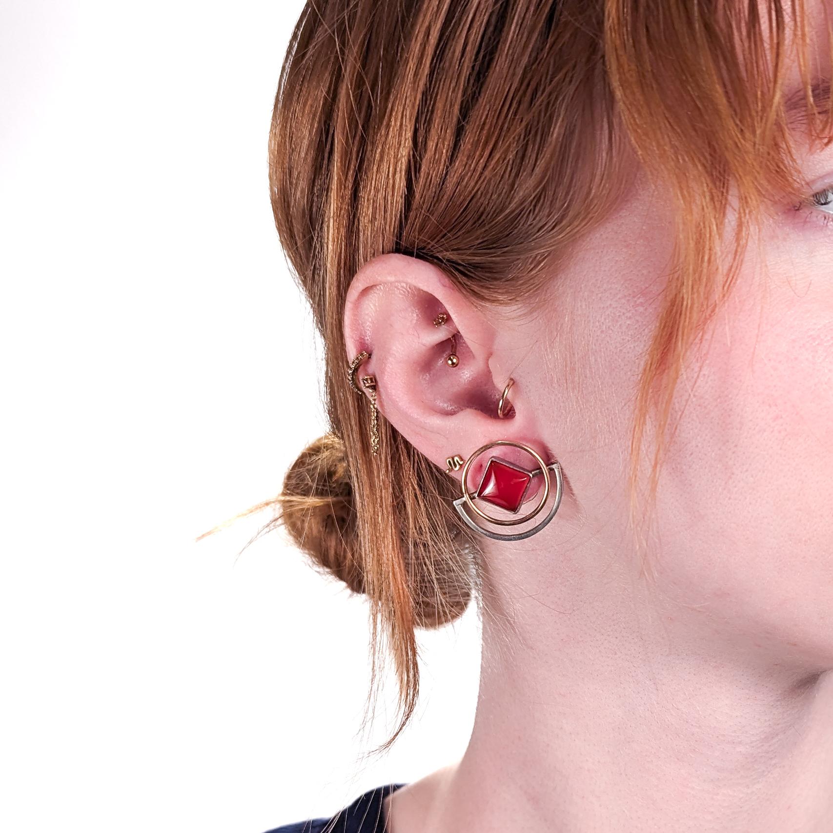 A pair of fine pair of retro geometric earrings.

In gold & silver with carnelian cabochons.

By Yumi Ueno. 

Ueno is a Japanese-American jewelry artist, whose fine and whimsical jewelry is informed by three-dimensional geometric abstraction. She