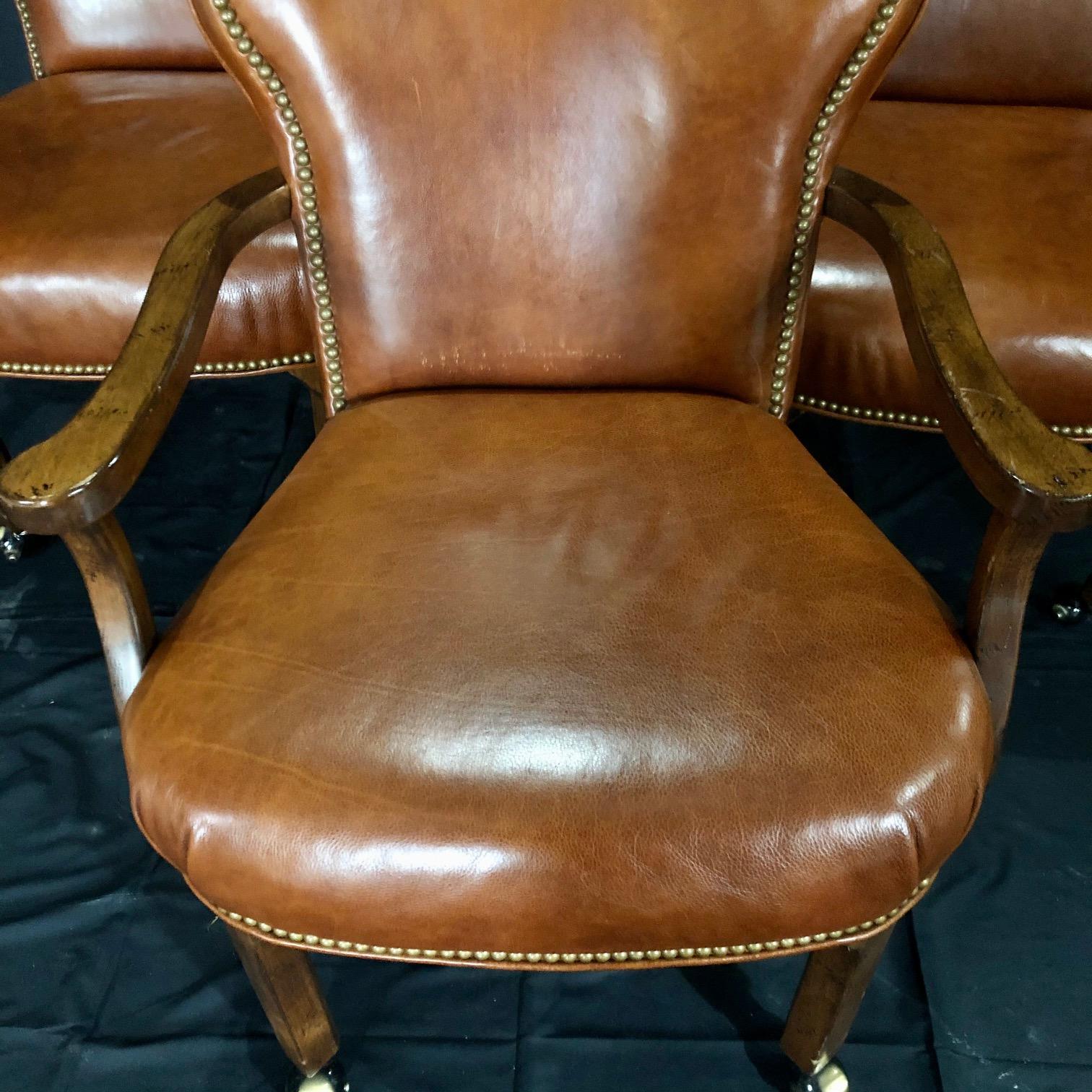 Handsome walnut caramel colored leather upholstered club chairs or library chairs having round shaped backs with brass nail trim and wooden legs terminating in casters, great shape and smooth rolling! #5212
Measures: Arm height 25.5
Note: Will