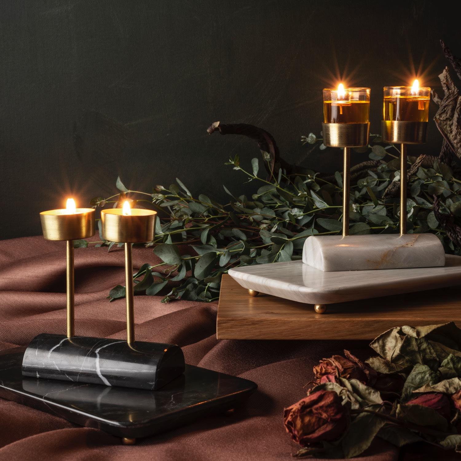Indulge in the exquisite beauty of the Yunta Tealight Candle Holder, a true masterpiece of artisanal craftsmanship. This decorative and luxurious piece combines a hand-carved marble base with two brushed brass poles, creating a visually stunning