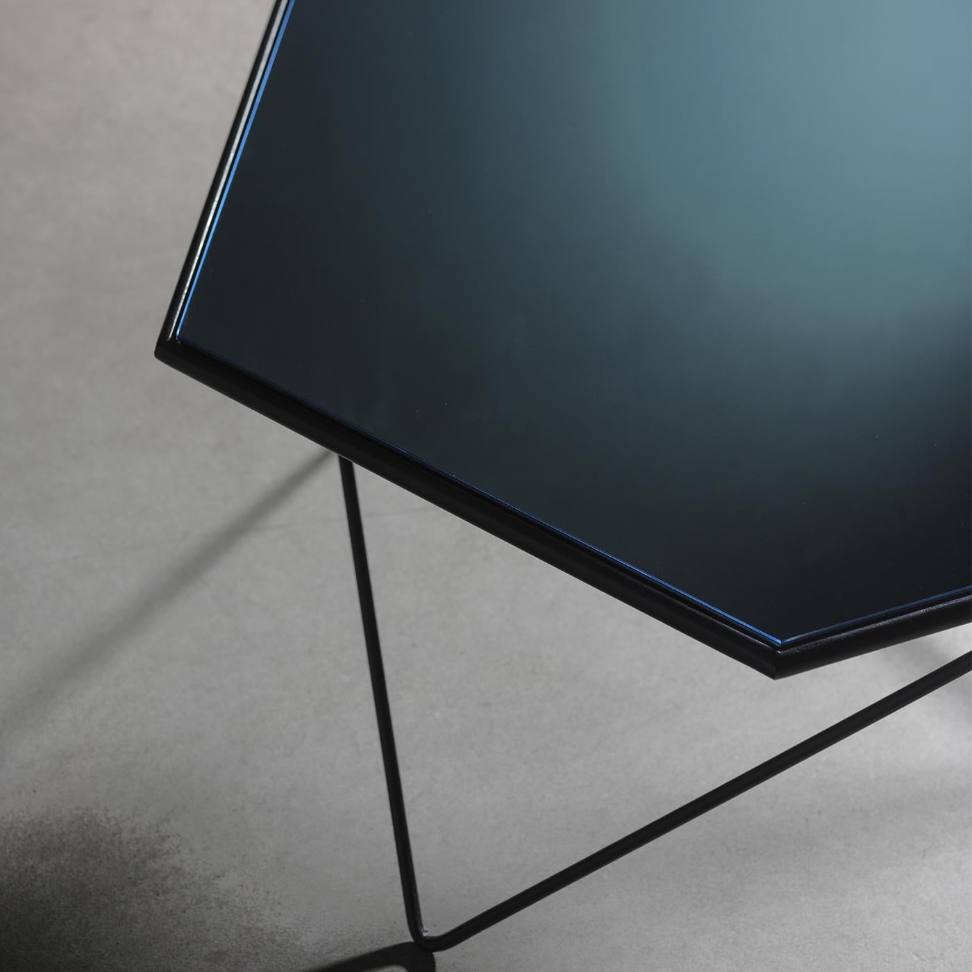 This unique, extremely modern coffee table stands out due to its geometric shapes and use of sleek materials. Its black metal base offers a play on thin, criss-crossing lines, while its hexagonal top features a serene, mirrored surface, creating an