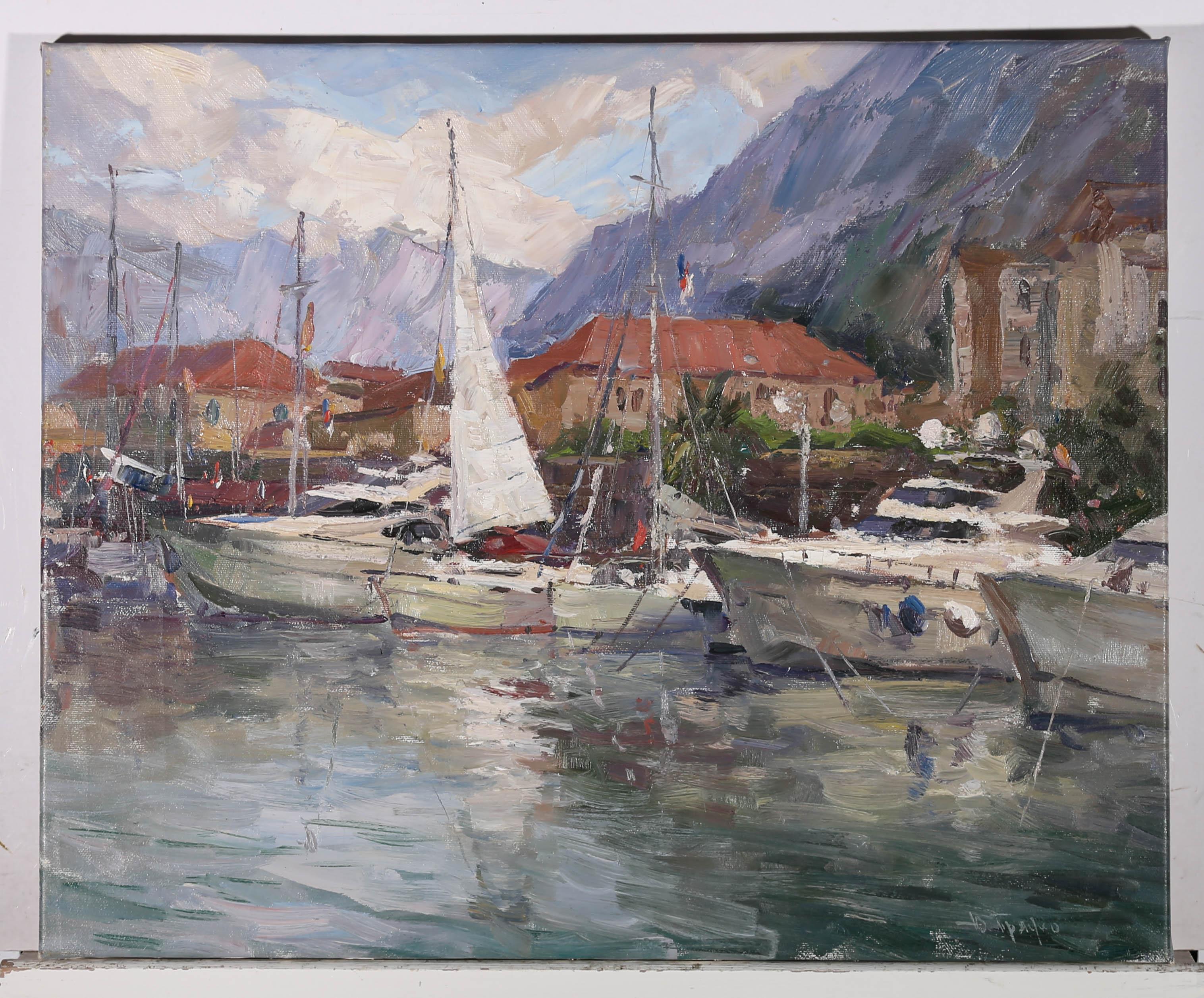 A fine 20th Century oil showing the beautiful harbour of Kotor in Montenegro. boats and small yachts float on the sparkling water with the impressive purple mountains looming in the distance. The artist has signed to the lower right corner and the