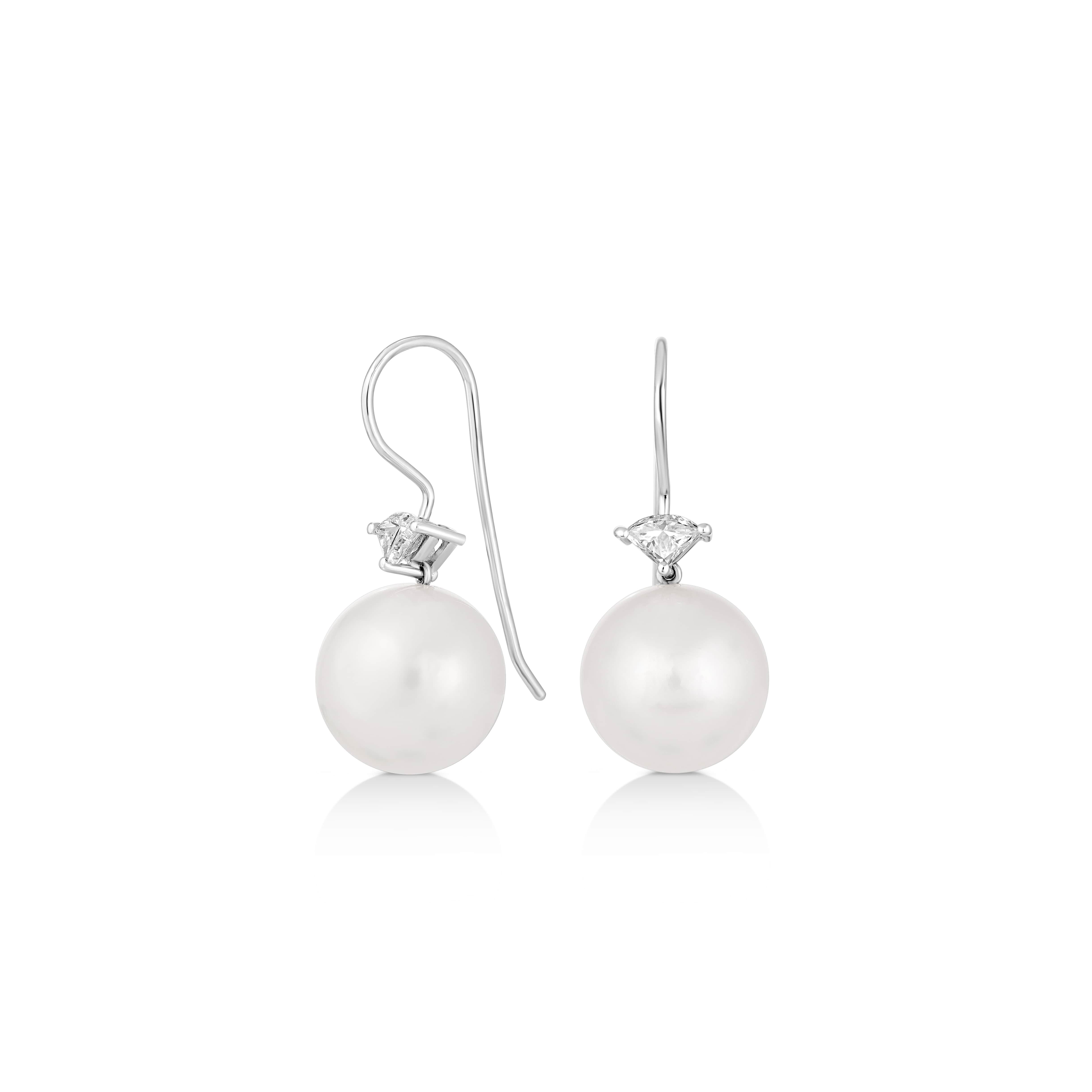 Illuminate any look with these captivating South Sea pearl earrings, exquisitely crafted in lustrous 18K white gold. Each earring is adorned with a pristine 12 mm natural South Sea pearl, known for its rich luster and roundness. Above the pearl, a