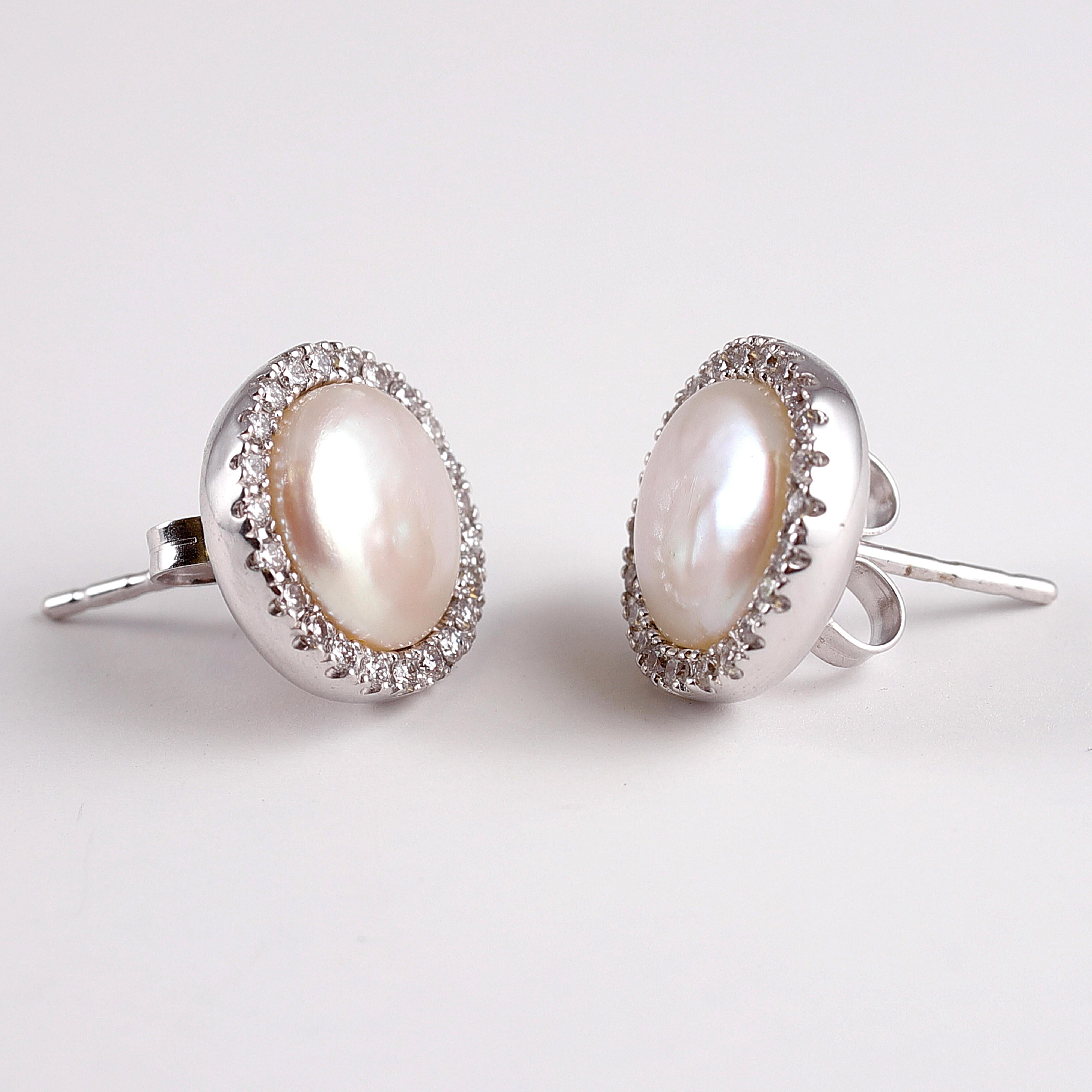 Cultured freshwater pearls with diamond halos in 18 karat white gold by Yvel.  These timeless earrings can be worn with so many things!