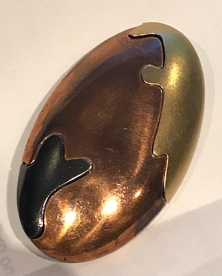 1980s Yves Saint Laurent abstract tri color oval brooc. Satin gold and gun metal grey plate with an antique patina on the copper plate front and back. The brooch is lightly domed and measures 2.63 inches wide, 1.5 inches long and .5 of an inch high.