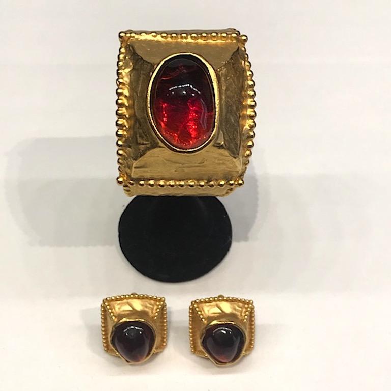 A stunning cuff bracelet and earring set from the 1980s by Yves Saint Laurent.  The set has a satin gold martele' finish and set with a large poured resin red brown cabochon. Along the edges of the cuff and earrings is a beadwork boarder. The cuff