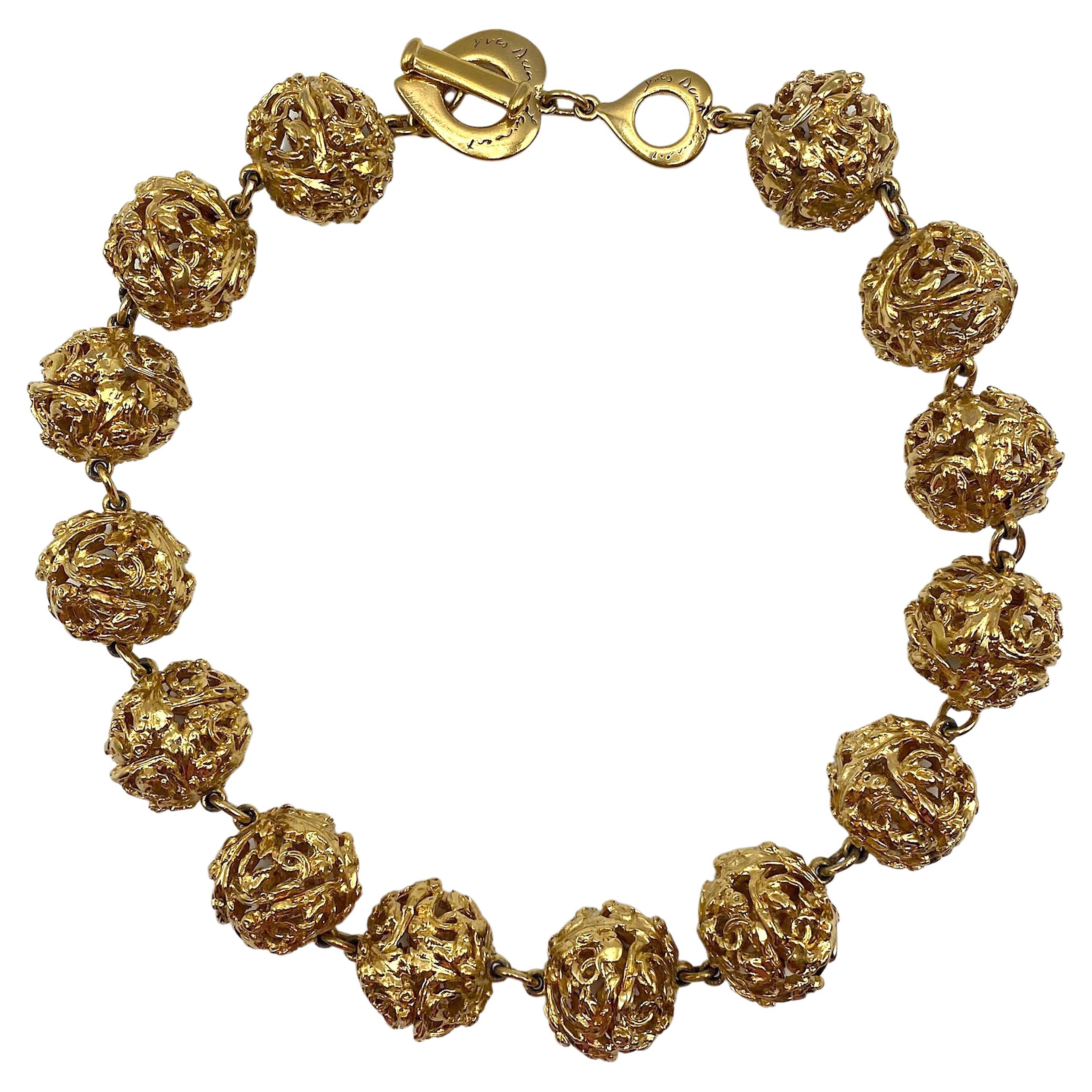 An elegant vintage Yves Saint Laurent classical and unique vine motif necklace from the 1980s. The piece is comprised of fourteen pierced and cast 18K gold plated balls .88 of an inch in diameter. Each ball is made of two semi spheres of of