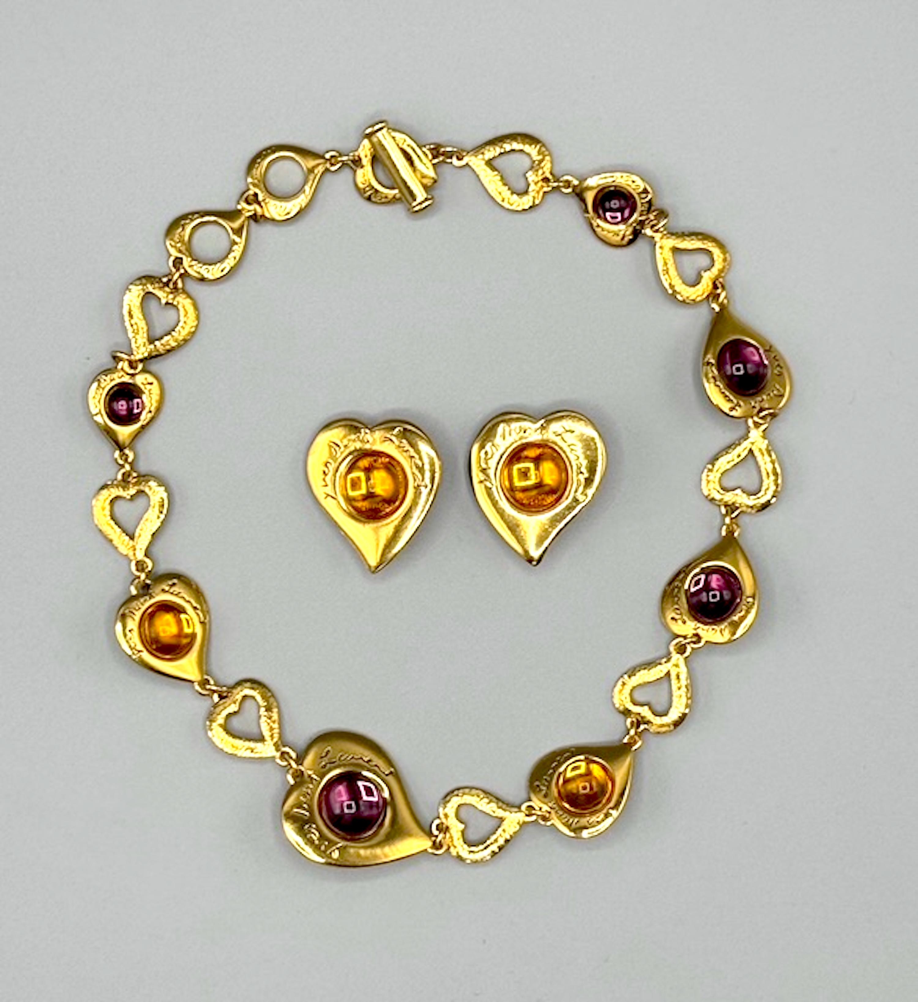Una splendida parure di gioielli degli anni '80 di Yves Saint Laurent. Le maglie della collana sono costituite da cuori grandi, medi e piccoli in oro satinato e ogni altro cuore reca la scritta Yves Saint Laurent. Sette dei cuori sono incastonati