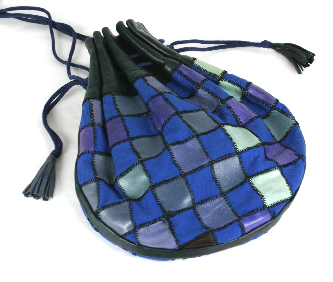 Rare, early Yves Saint Laurent  spring summer 1980 Flat drawstring pouch of patch worked leather and canvas. Multicolored patchwork canvas in royal blue with purple, grey and green-blue leather with black topstitching. Long black leather straps with