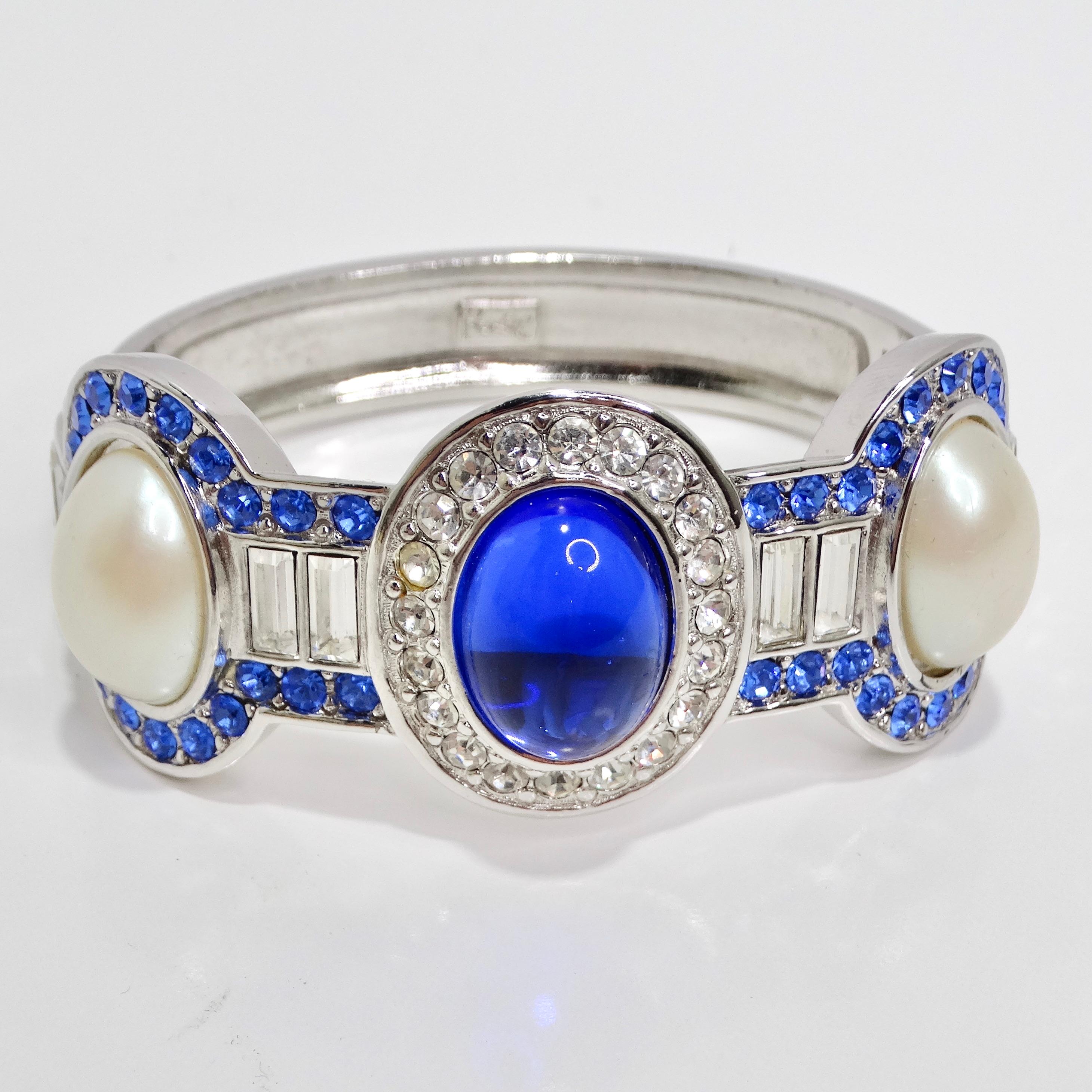 Introducing the Yves Saint Laurent 1990s Faux Sapphire Pearl Clamper Bracelet, a glamorous and captivating accessory that perfectly captures the essence of the fashionable era. This silver-tone clamper bracelet boasts a sophisticated design with