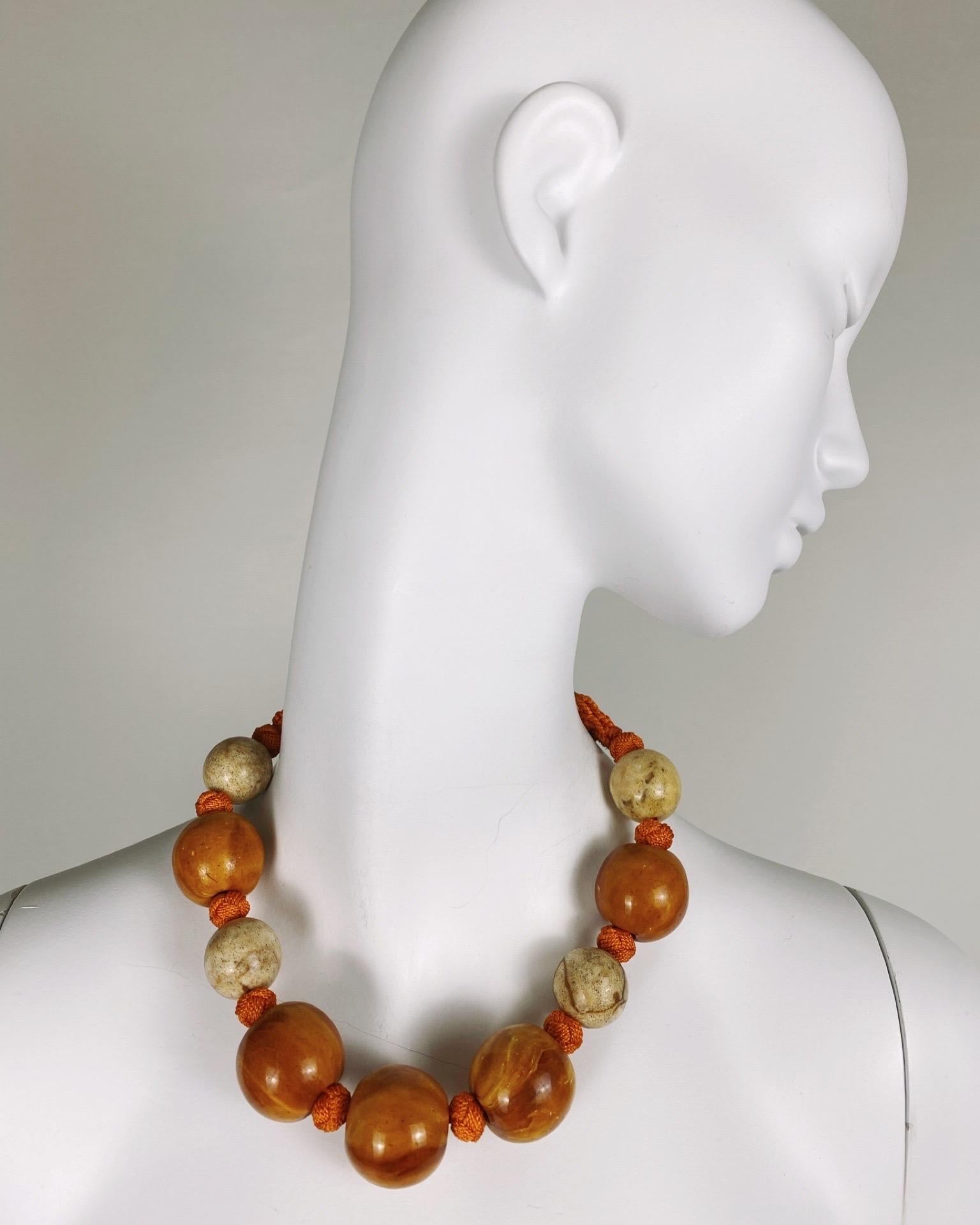 A striking and highly collectible Yves Saint Laurent statement necklace from the 1990s, showcasing the designer’s bold and eclectic aesthetic. This piece features oversized round beads in warm amber-orange and cream tones, hand-strung on a vibrant