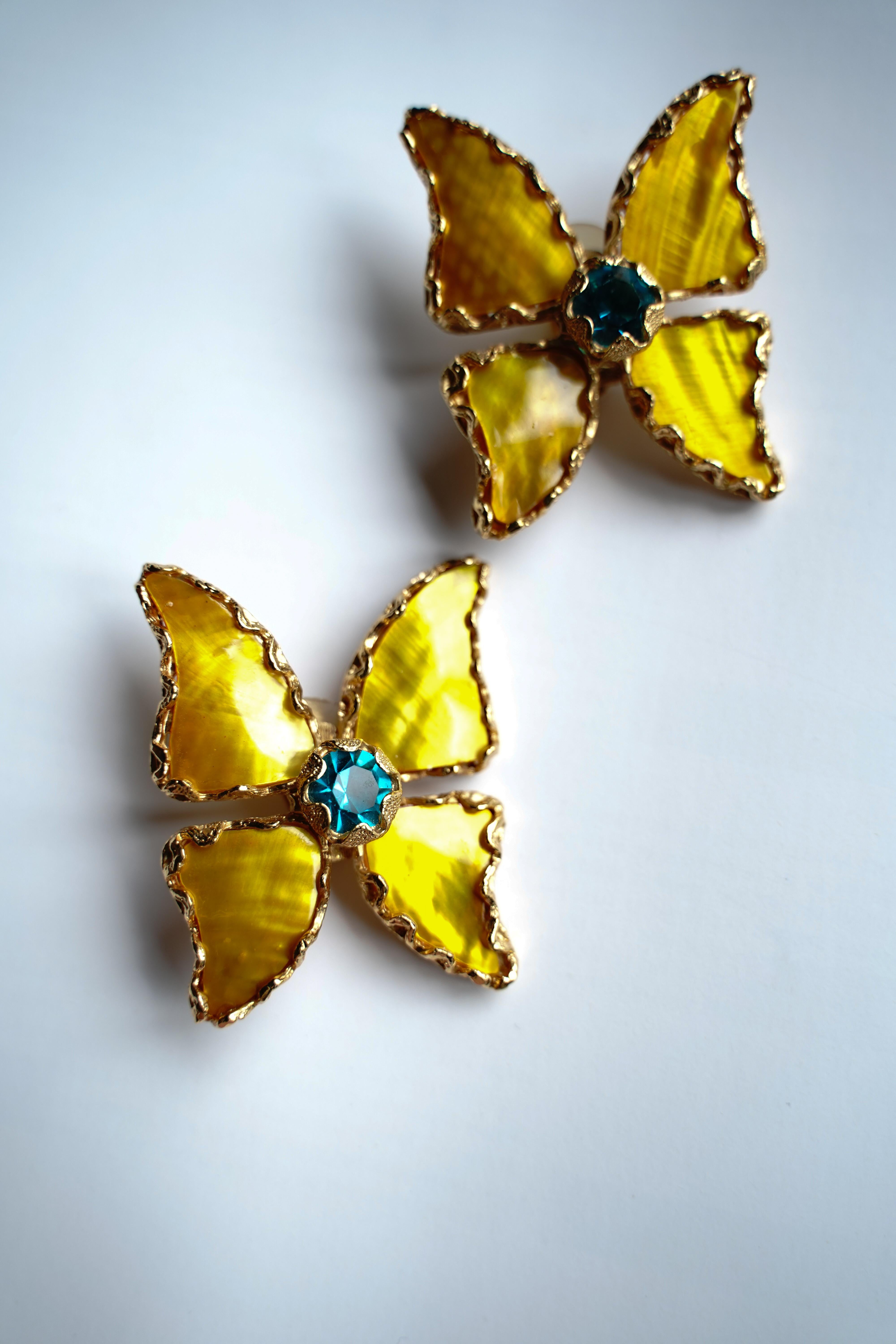 Spettacolari ed emblematici orecchini a clip da passerella della collezione Rive Gauche 1993 di Yves Saint Laurent.
Nel cuore di ogni farfalla si trova un cristallo blu vivo, sfaccettato per catturare e riflettere la luce con una brillantezza