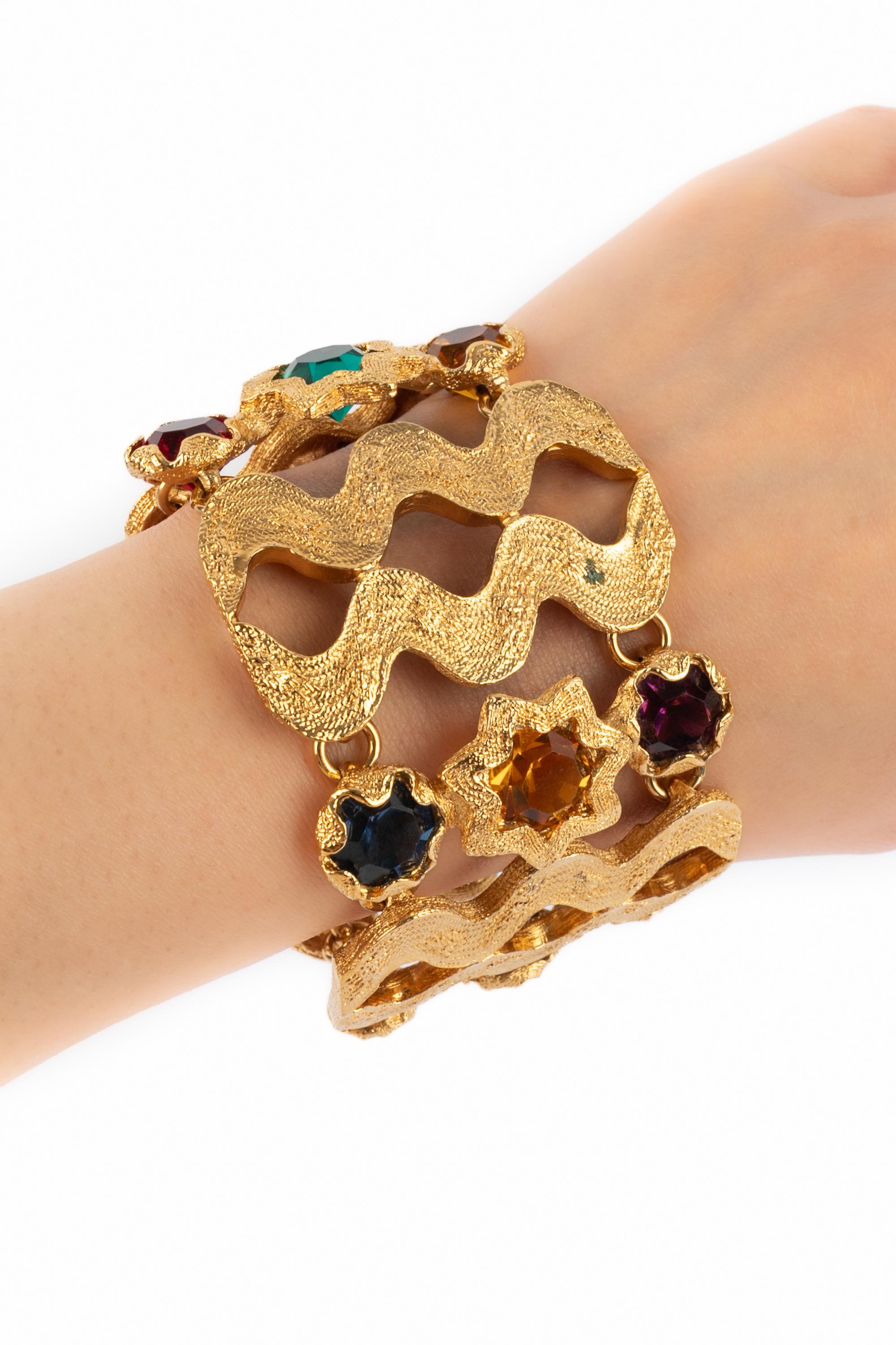 YVES SAINT LAURENT - (Made in France) Wide golden metal articulated bracelet ornamented with colorful rhinestones.

Condition:
Very good condition

Dimensions:
Length: 17.5 cm - Width: 5 cm

SKU:BRA118