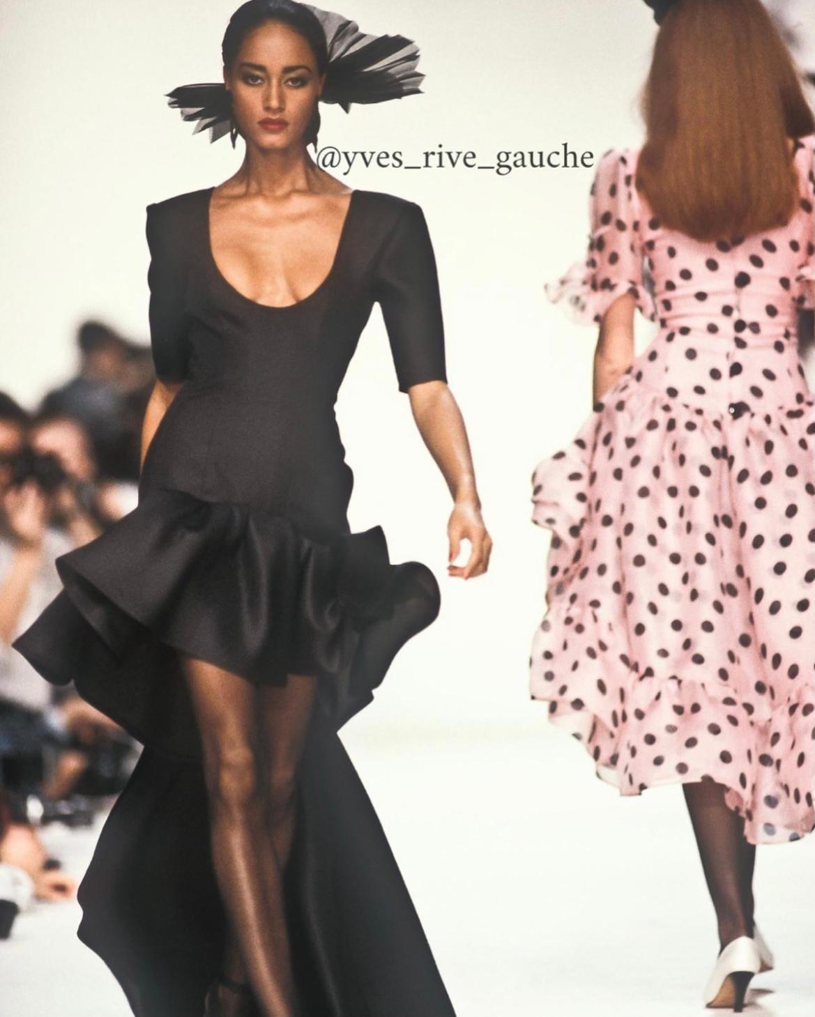 Celebrate the magic of getting dressed-up for a special occasion with this standout SS1990 runway evening piece by YSL ! Cut from black silk gazar to hug the curves, this dress features short sleeves, an asymmetric skirt and a bow train. The deep