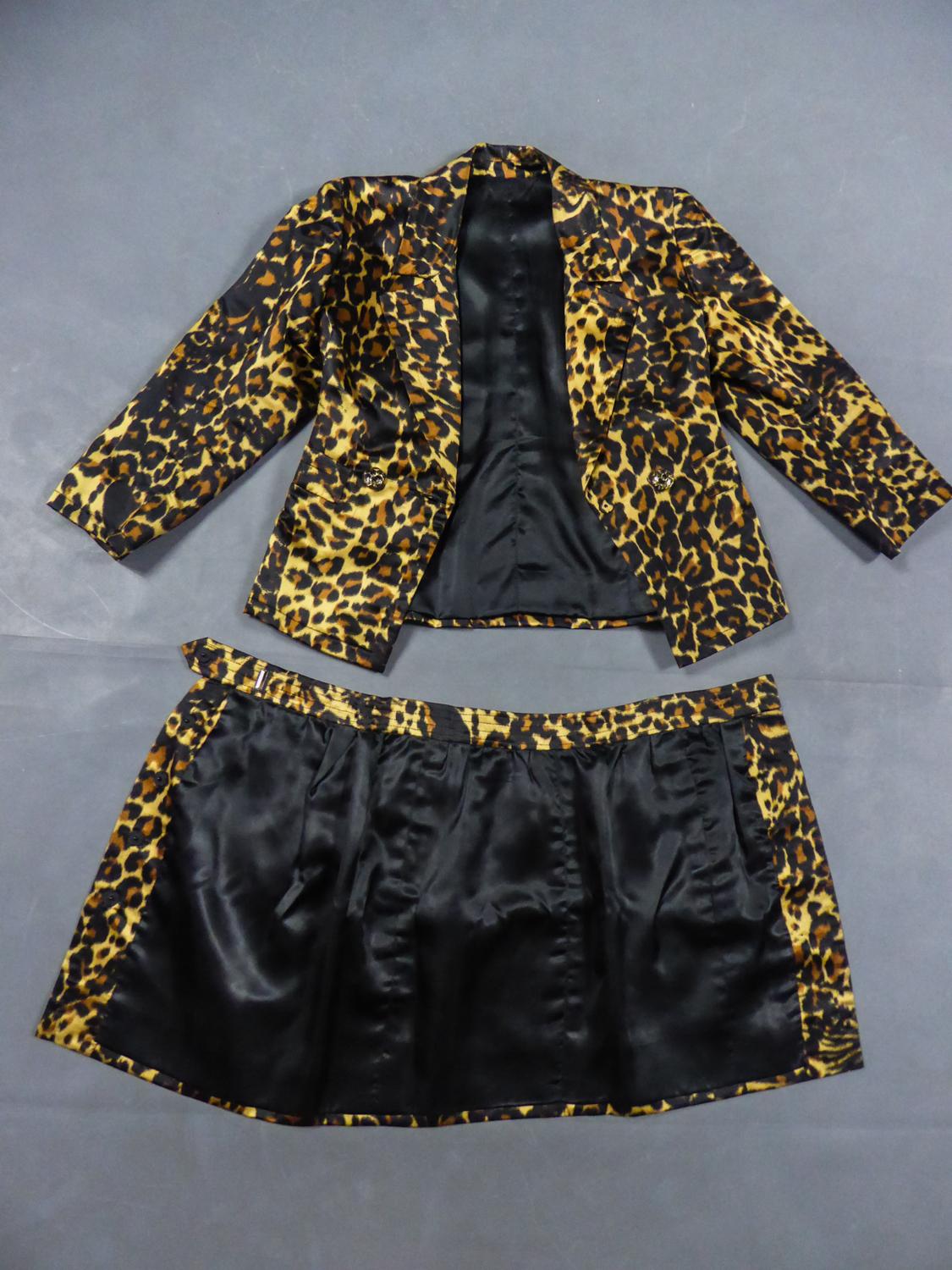 Circa 1990
France

Yves Saint Laurent Skirt suit without label from the 1990s. Set in printed panther silk satin. Crossed jacket with topstichting, large lapels and pockets. Translucent buttons with golden panther effect. Short wrap skirt with side