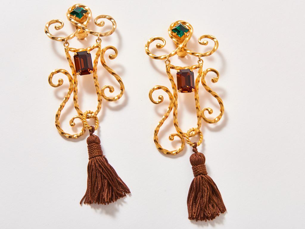 Yves Saint Laurent, gold tone, baroque motif,  jumbo size, clip on earrings, having topaz and emerald, colored cut stones detail, and brown tassels that sweep the shoulders.