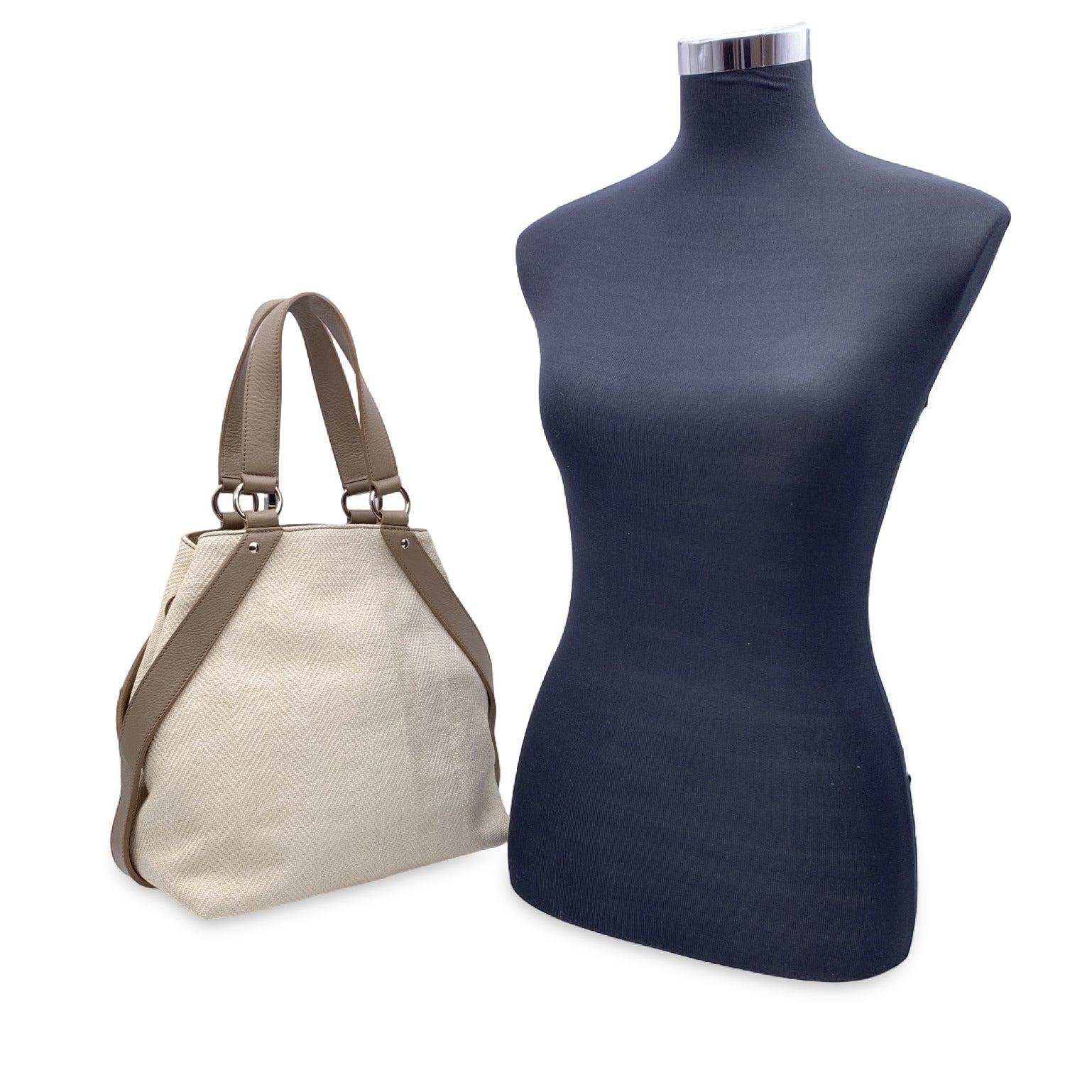 YVES SAINT LAURENT beige canvas tote bag with grey taupe leather trim. The bag features silver metal hand, Y-shaped lrather trim on the sides, open top and double top handles. Beige fabric lining. 1 side zip pocket inside. 'Yves Saint Laurent' tag