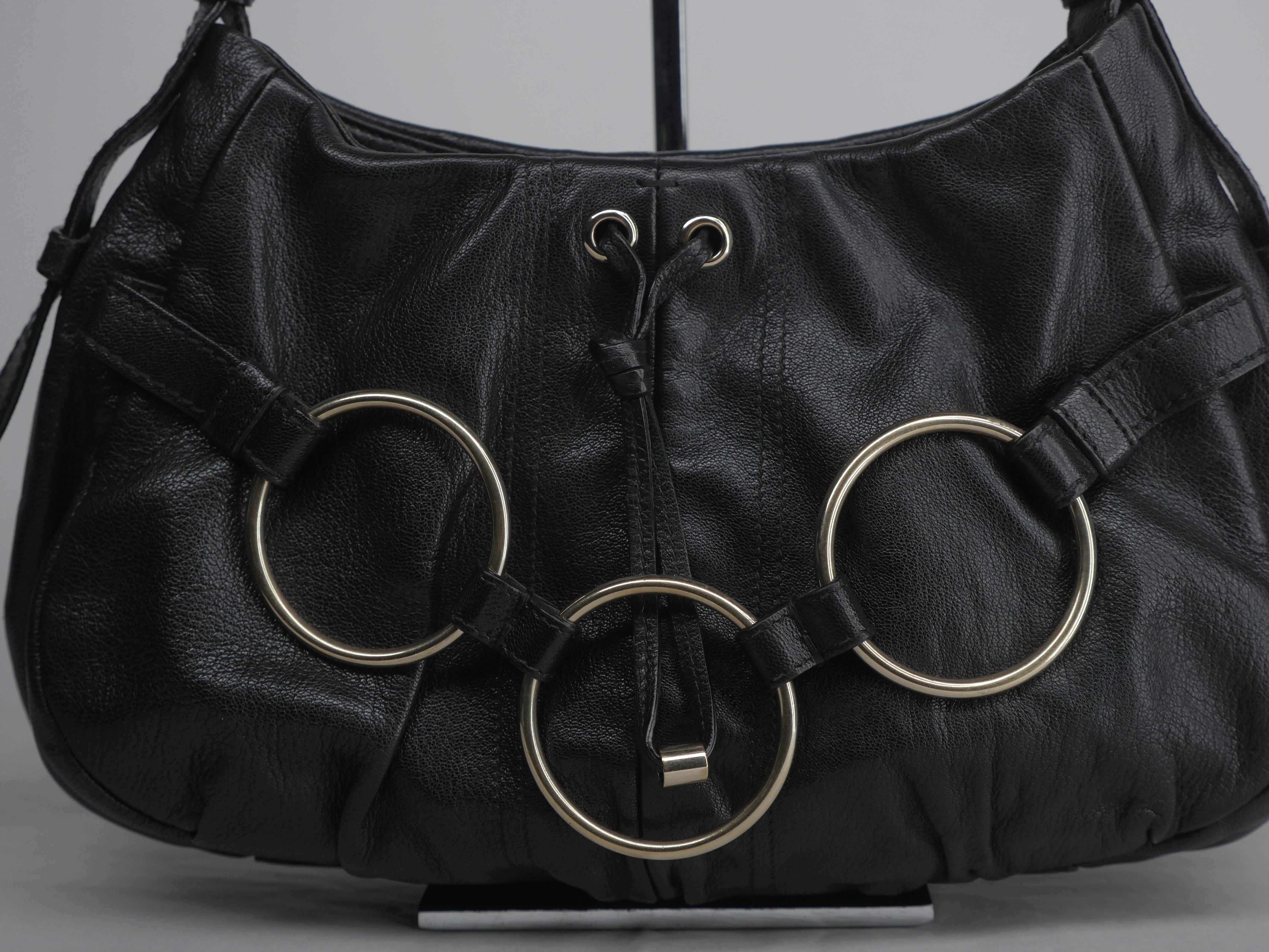 Shoulder Bag with gold circular link hardware and tassel detail. Zipper Top and adjustable strap
