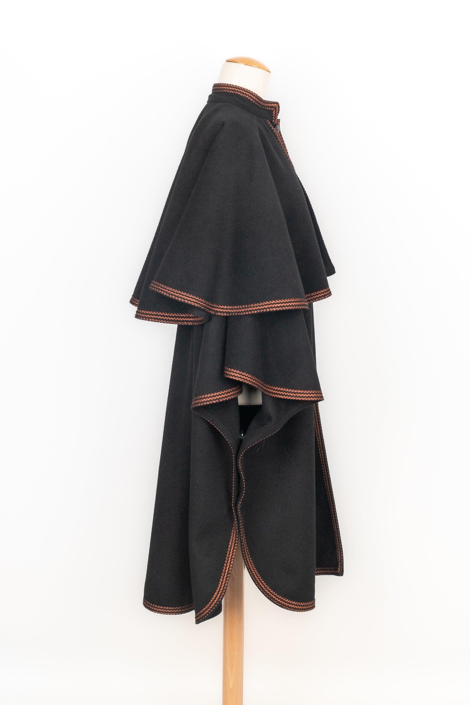 Yves Saint Laurent - Black blended wool coat with cape style and edged with trimmings. No size indicated, it fits a single-size.

Additional information:
Condition: Very good condition
Dimensions: Sleeve length: 105 cm - Length: 47 cm

Seller