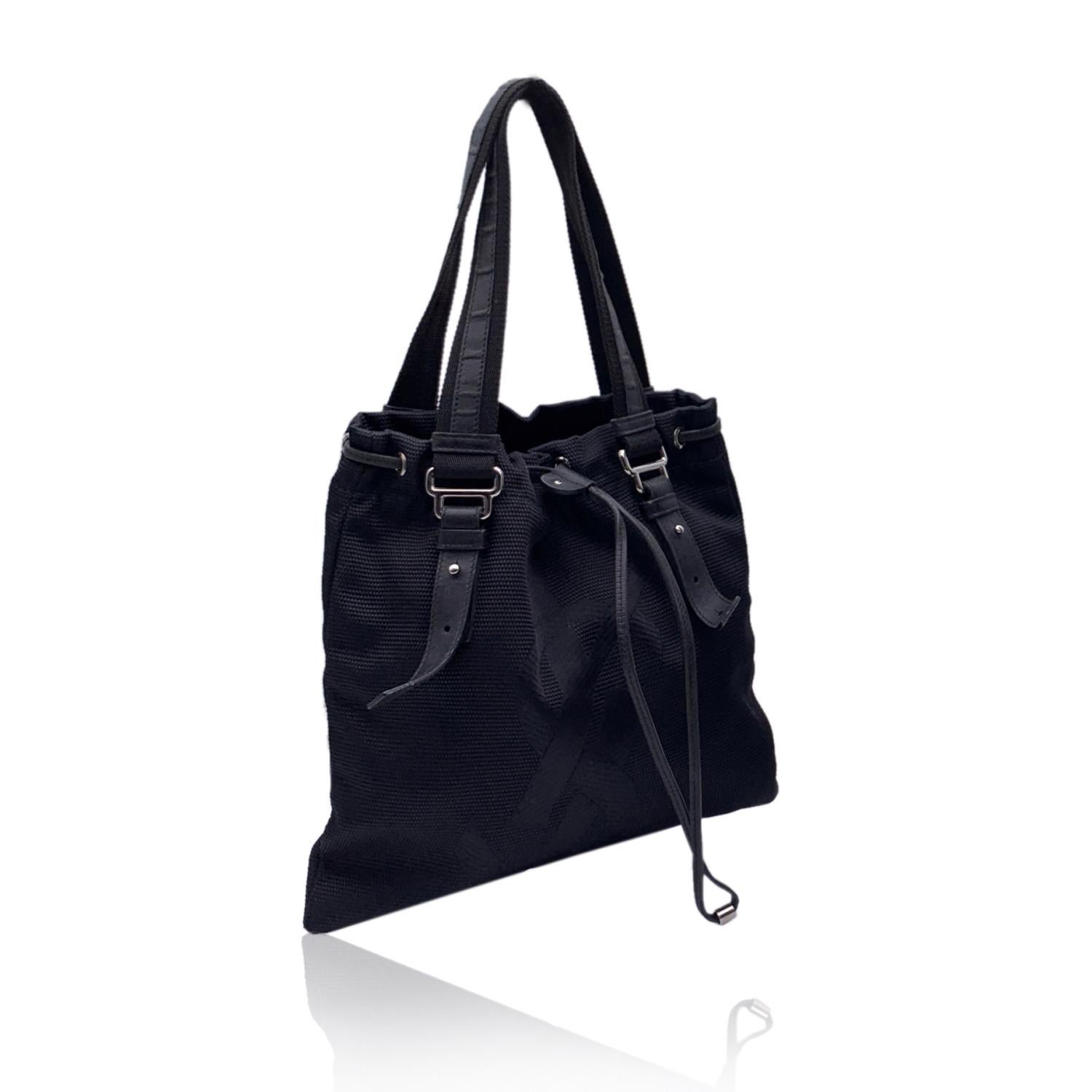 YVES SAINT LAURENT Black canvas 'Kahala Sac' tote bag, with jacquard YSL logo on the front. Drawstring closure on top. Double canvas and leather handles. Black satin lining. 1 side zip pocket inside. 'YVES SAINT LAURENT Rive Gauche' tag inside