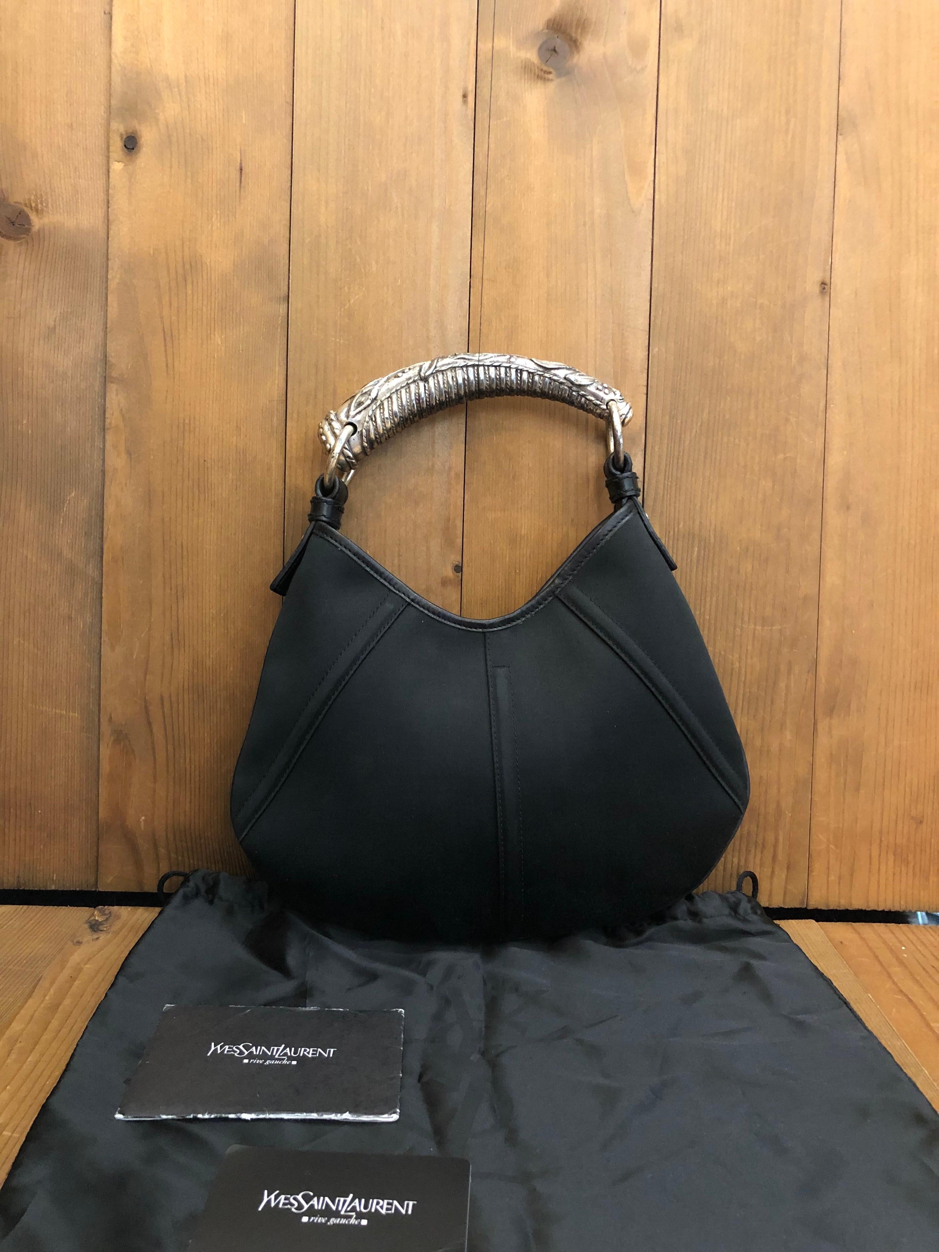 This iconic Yves Saint Laurent Mini Mombasa hand bag from the 2000's by Tom Ford features a sculptured metal handle. Comes with booklet and dust bag. Crossbody chain seen in the picture is complimentary.

Material: Canvas/Leather/Metal 
Color:
