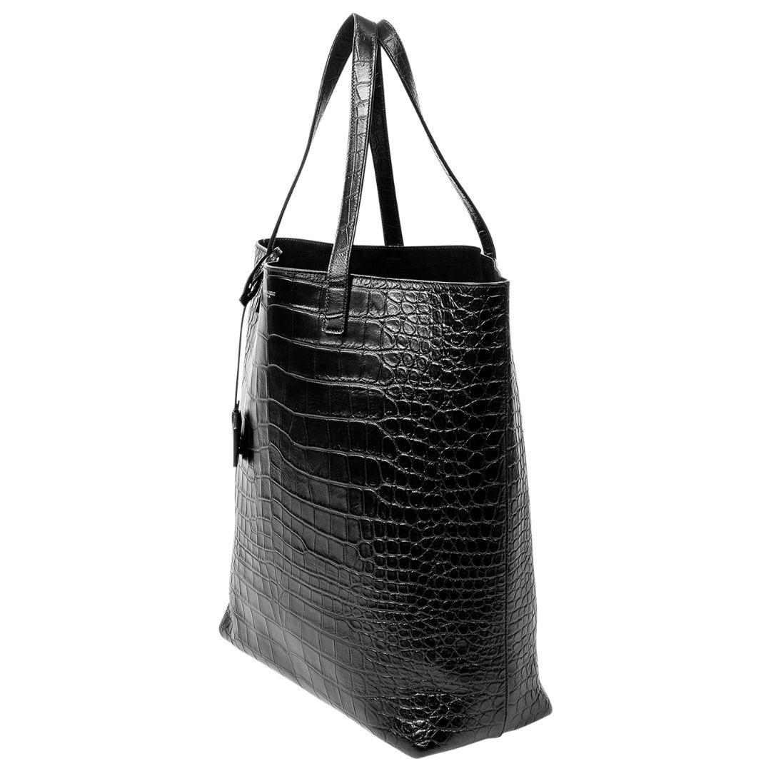 Make a bold and luxurious statement with this black crocodile embossed leather bold tote. Crafted from crocodile-embossed leather in classic black, this tote exudes elegance. The silver hardware and open top design add a modern touch. The leather