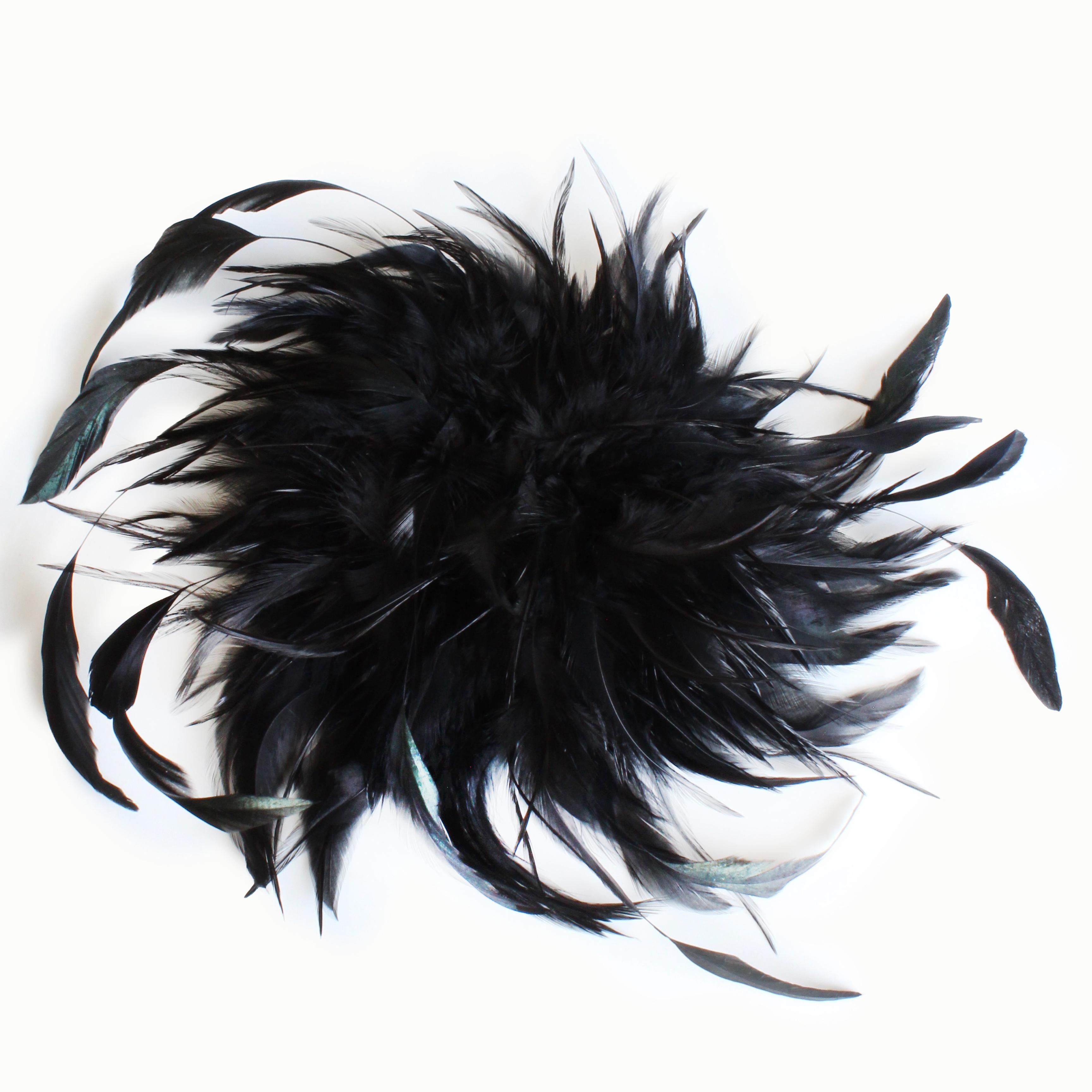 This rare feather cap was made by Yves Saint Laurent, most likely in the late 70s or early 80s. Made from a combination of black ostrich and longer plume feathers with black fabric layers in between, all of which are affixed to a netted fabric base