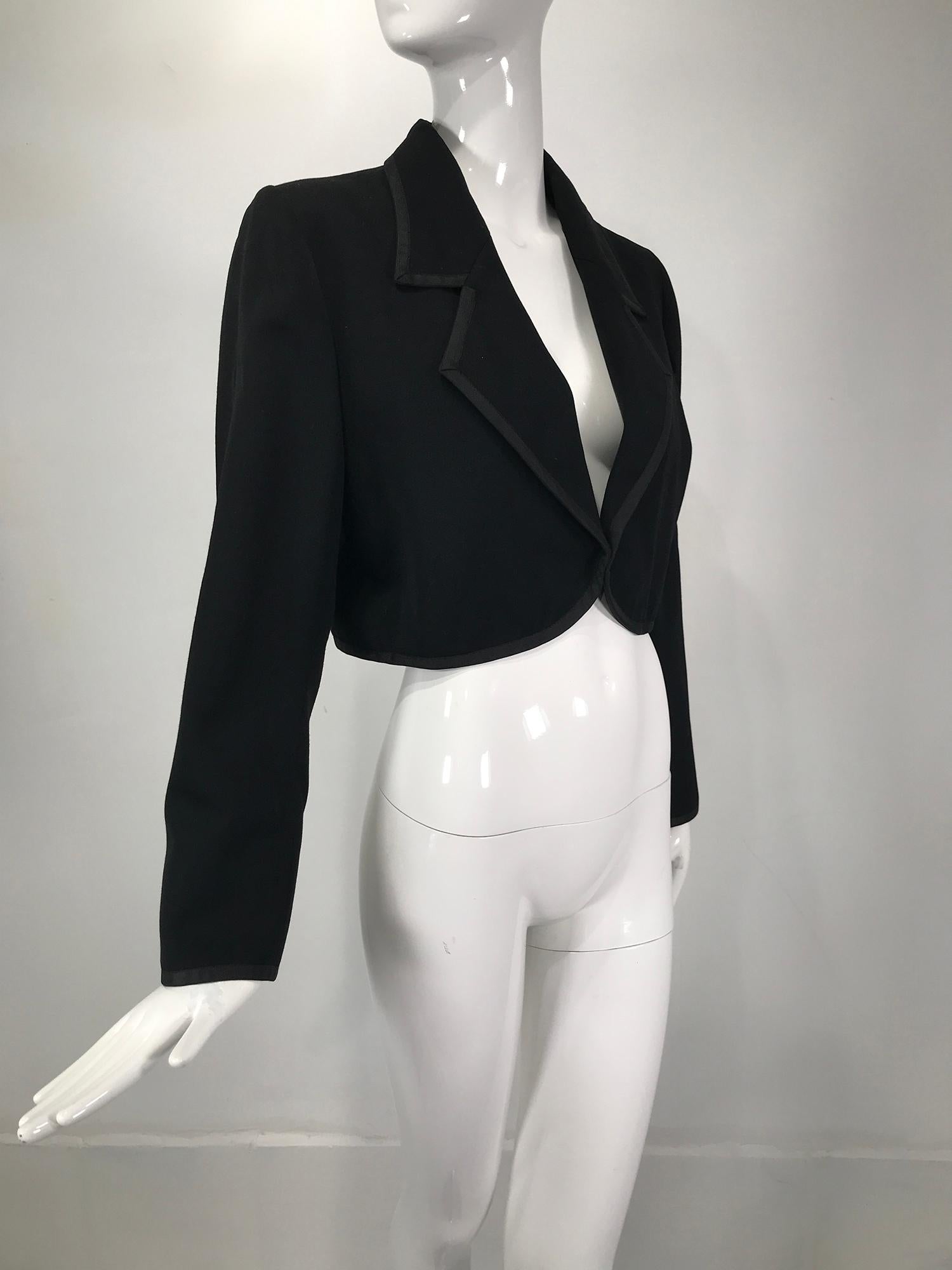 Yves Saint Laurent Rive Gauche black gabardine cropped jacket with braid trim from the 1970s. Open front jacket with notched lapels, long sleeves with button cuffs, cropped above the waist, fully lined. Marked size 42. In very good pre-owned
