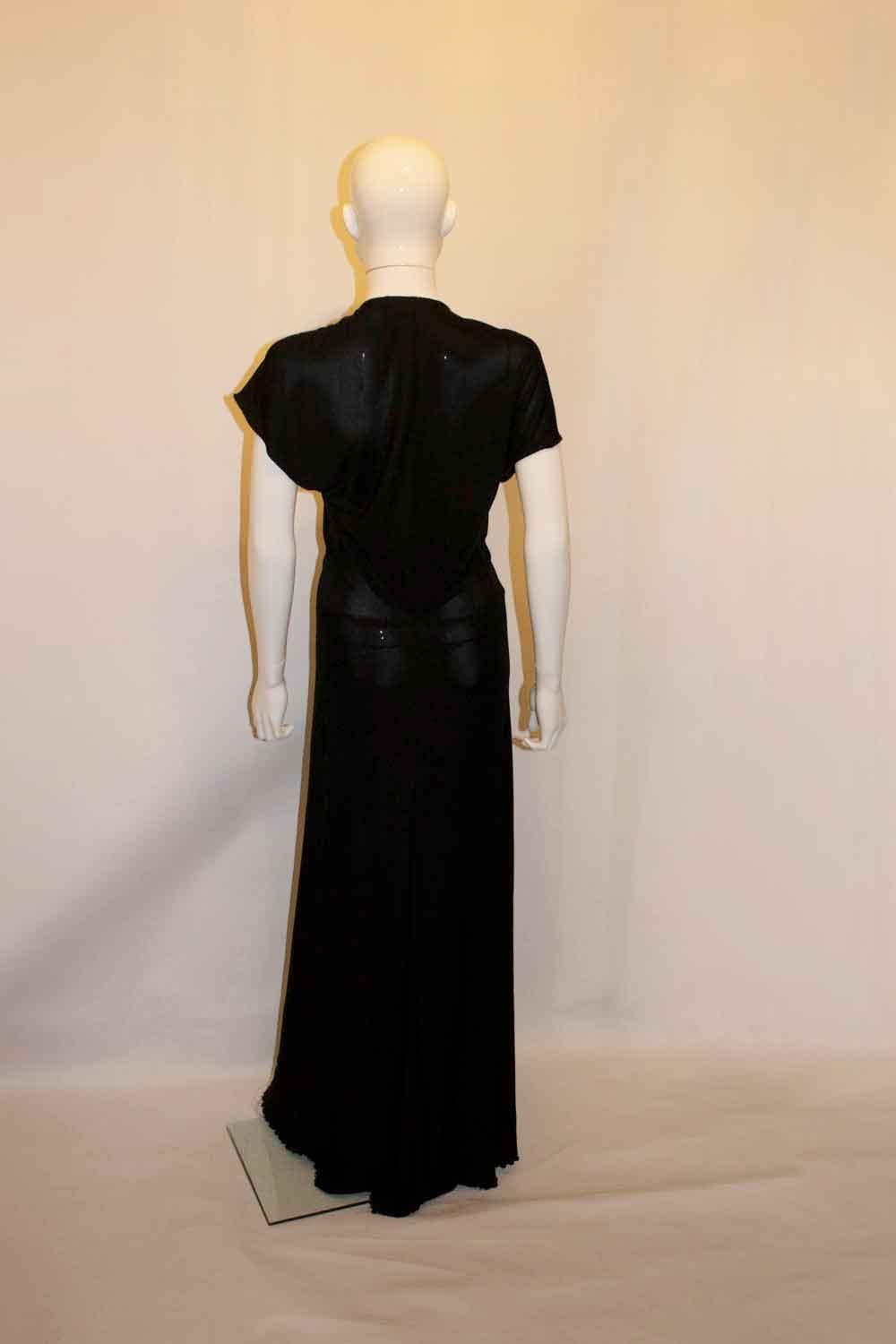 A chic black evening gown by Yves Saint Laurent. The dress has a v neckline with woven detail at the front under the bust, and gathering. It has cap sleaves. Size 38. Bust up to 36/8'' length 66''