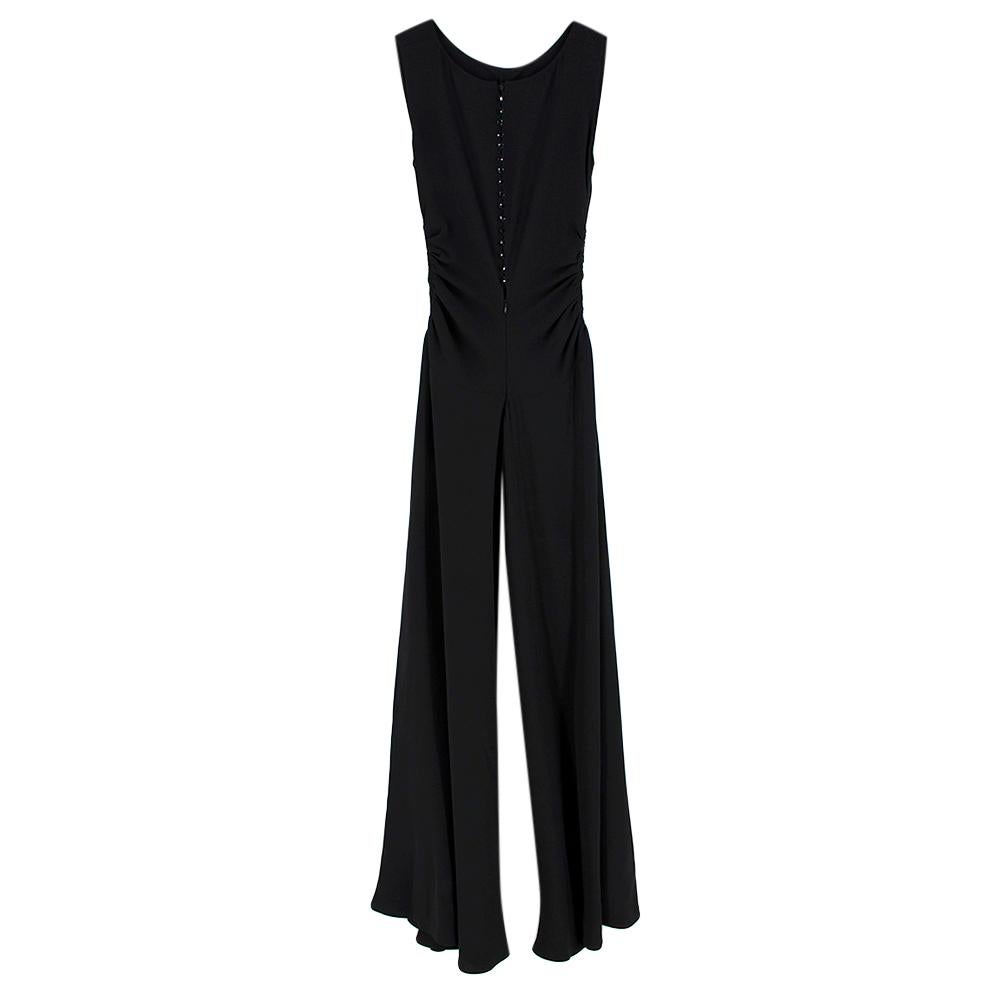 Yves Saint Laurent Black Jumpsuit with Ruffled Details 

-silky touch 
-black crystal-like button fastening to the back 
-Ruffled details to the sides 
-Trompe loeil wide pants, resembling a skirt  
-Invisible zip fastening to the back 

Materials