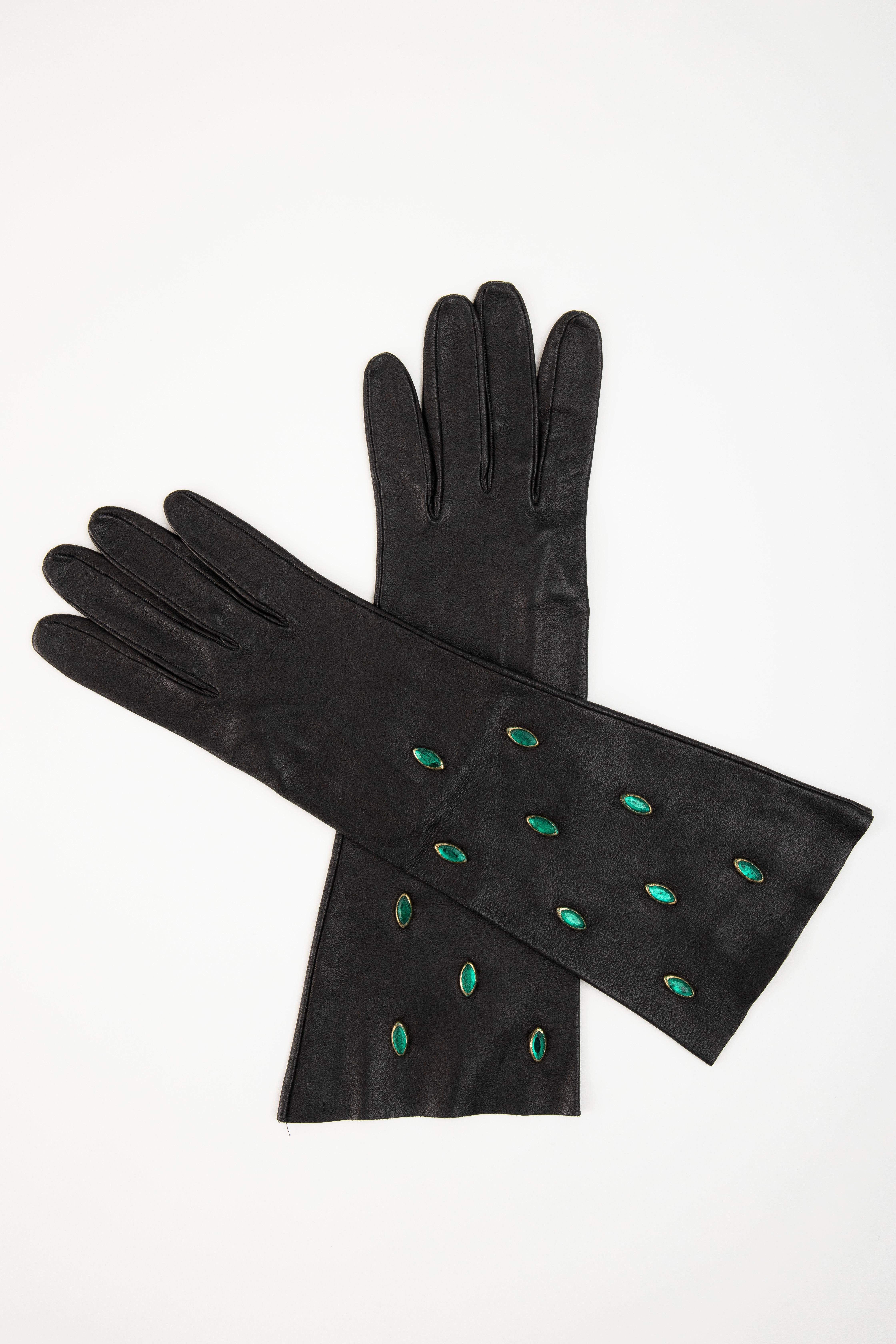 Yves Saint Laurent, Circa:1980's black leather gloves with appliquéd marquise shaped green glass and suede interior.
 No Size Label

Fits: 7- 7.5

Length: 14.25