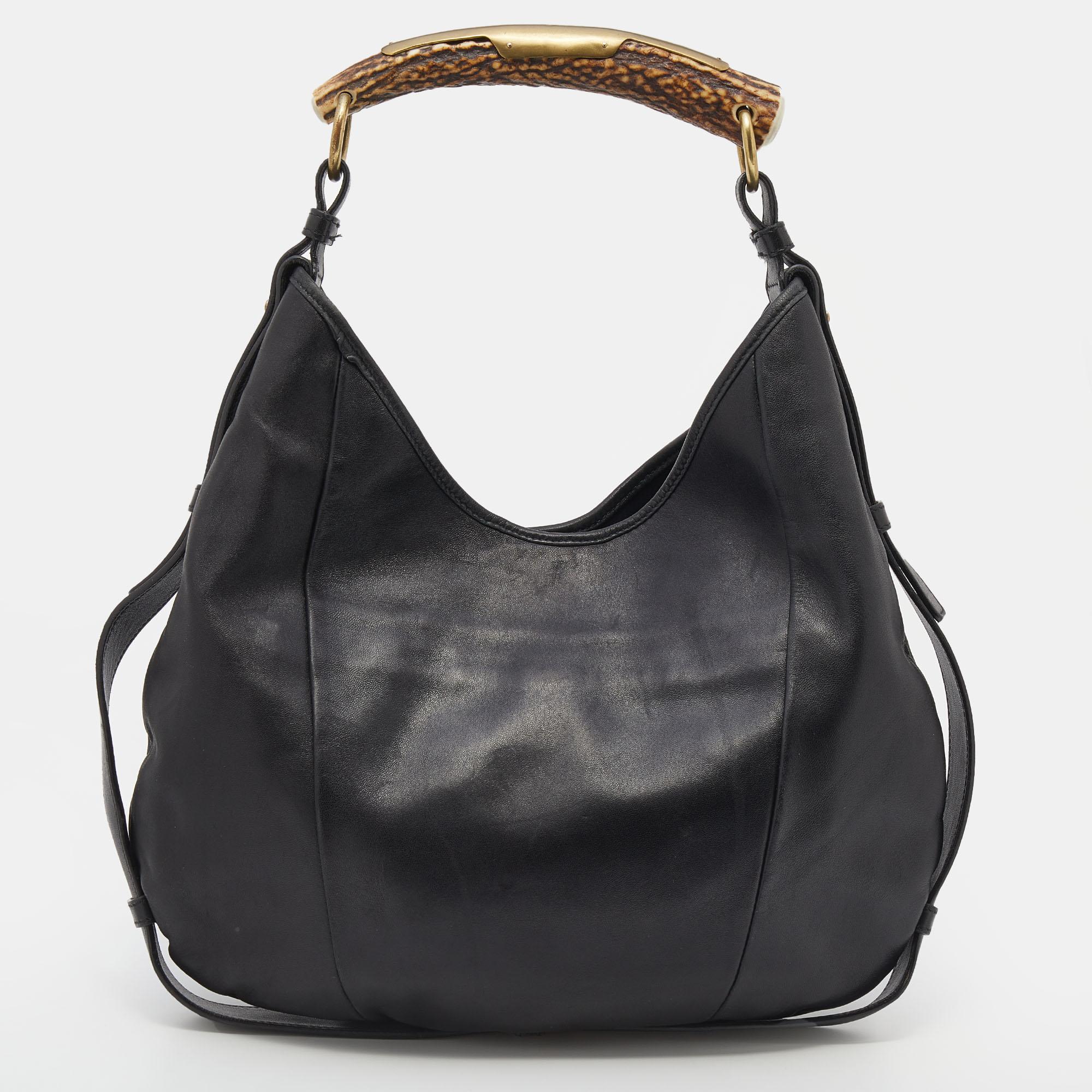 This Mombasa hobo from the House of Yves Saint Laurent is made to grant you complete practicality and luxury! Made from black leather, this hobo is decorated with a horn detail. It has a spacious satin-lined interior and gold-tone hardware. This