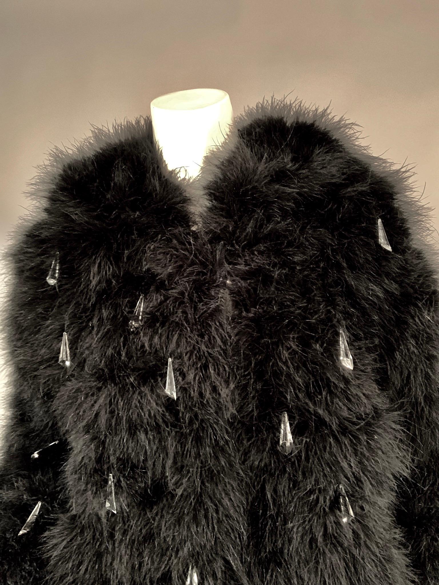 Does this glamorous 1970's feather coat from YSL tickle your fancy? It is made from black marabou feathers with a rounded collar, two fur hooks for closure at the center front and sparkling plastic prisms dangling and catching the light with your