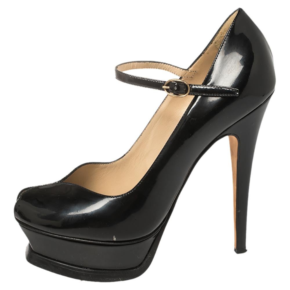 This Yves Saint Laurent pair of black glossy pumps is a classic Mary Jane shoe with a modern twist. They have been meticulously crafted from patent leather in Italy. A peep-toe silhouette, solid platforms, delicate ankle straps, and 13 cm heels add