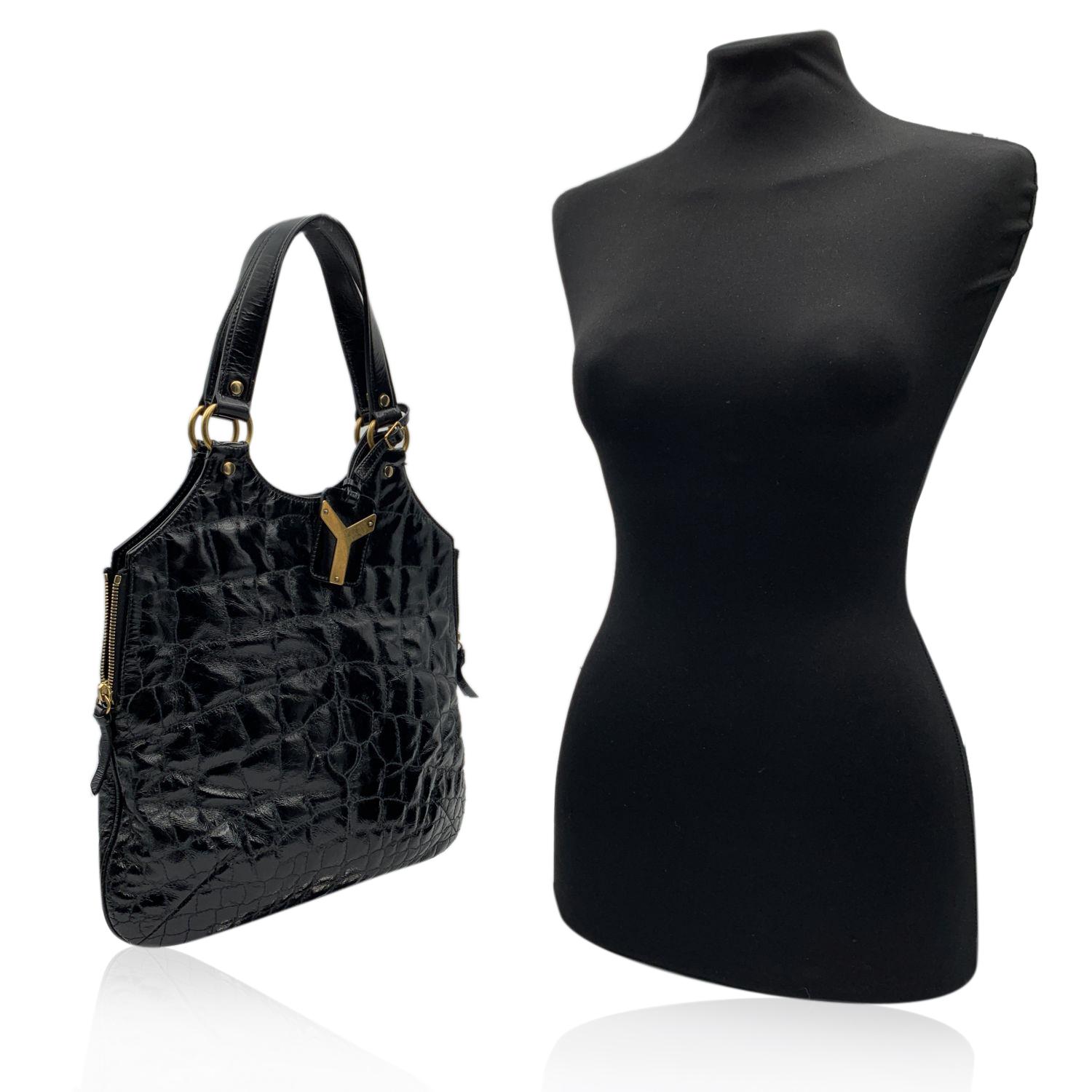 Yves Saint Laurent Black 'Metropolis Tribute Bag', crafted in black shiny leather with a quilted embossed croc-look. It features a sleek design in with side zip detailing , an ID tag and gold metal hardware. Magnetic button closure on top. Black