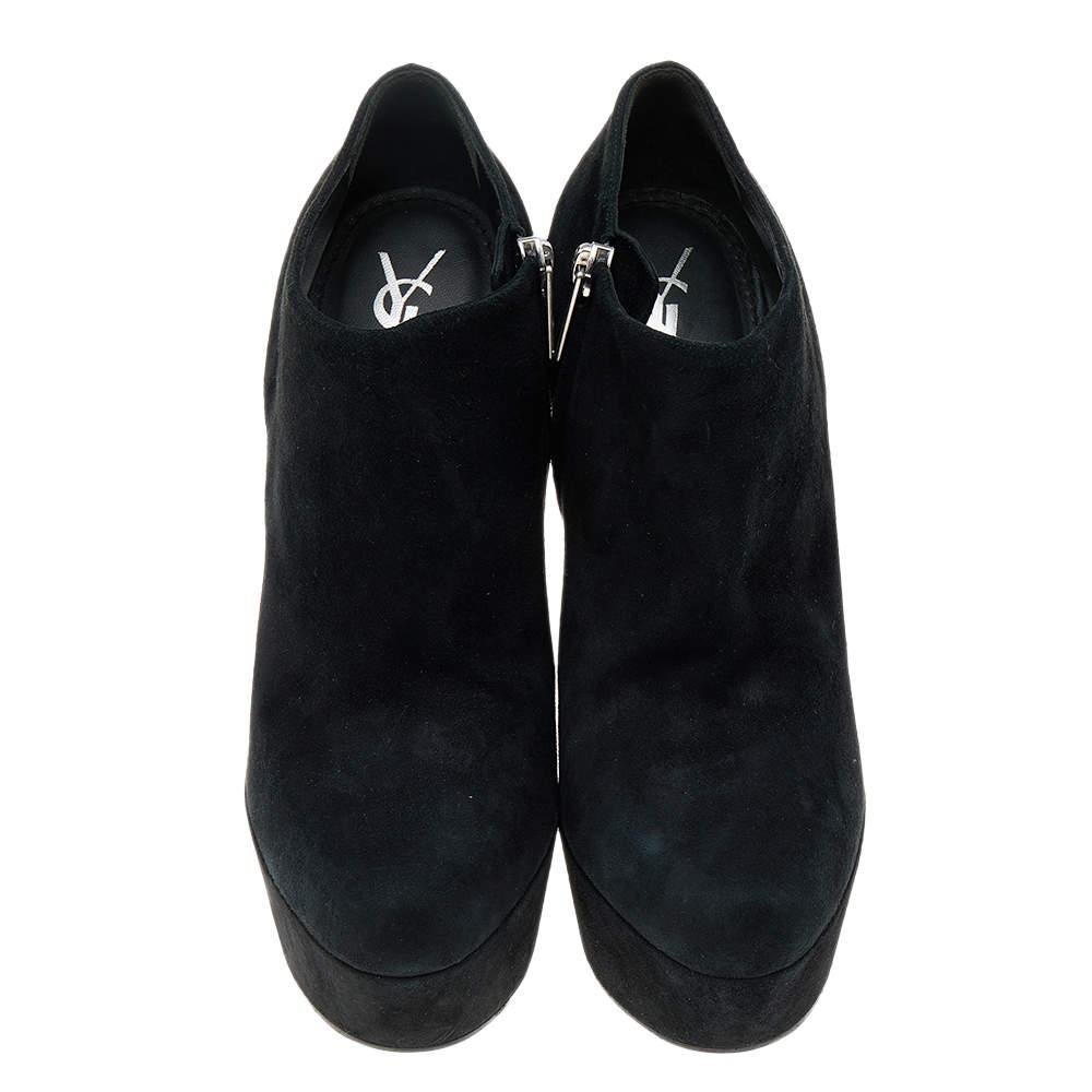 Ajoutez une touche de classe à vos pieds avec ces bottes de la maison Yves Saint Laurent. Elles sont réalisées en daim noir sur l'extérieur et présentent des orteils couverts, des accessoires argentés, des semelles compensées et une fermeture à