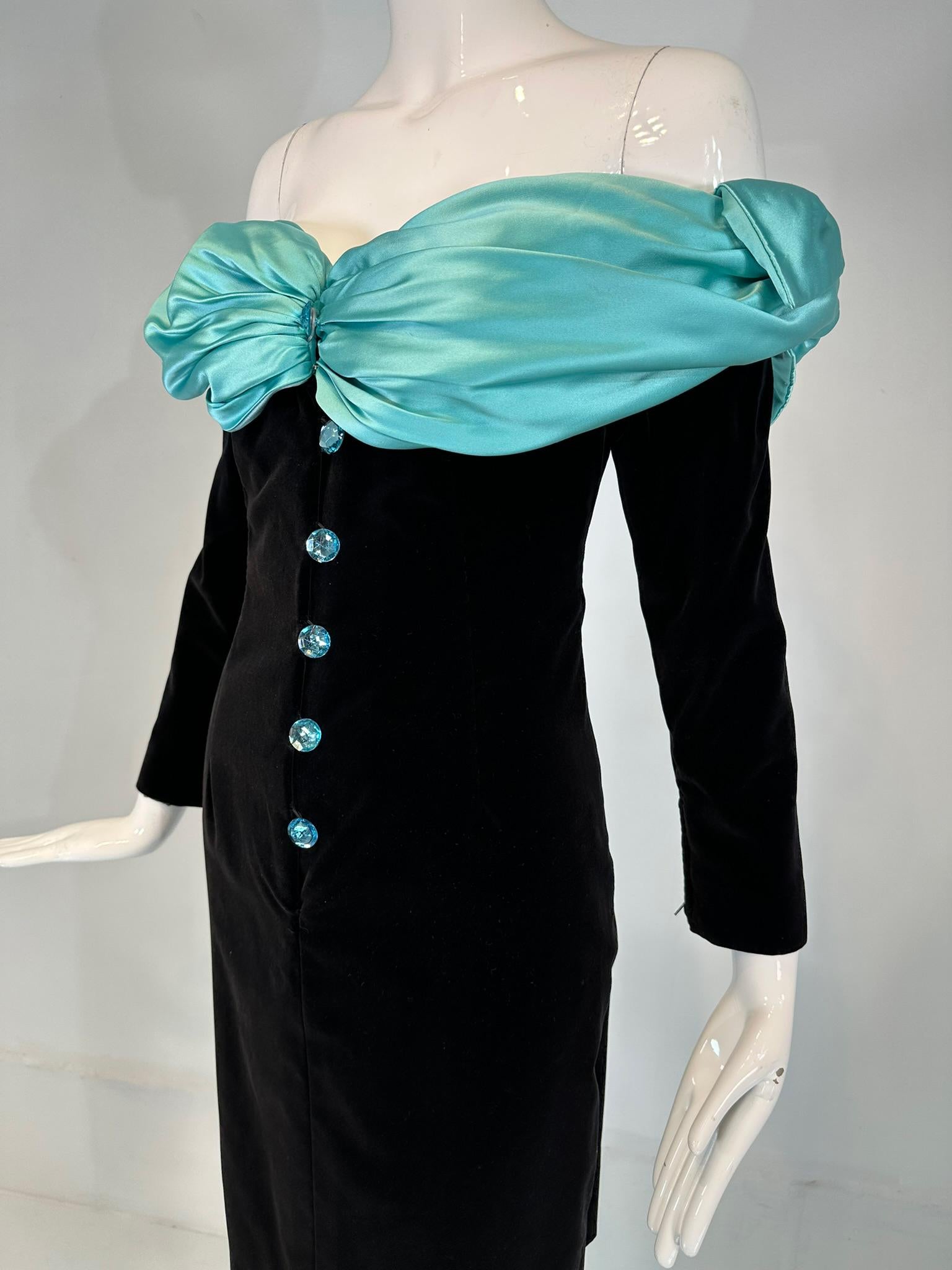 Yves Saint Laurent black velvet with turquoise satin, off the shoulder, attached cape cocktail dress from the 1980s. Fitted sheath dress of black velvet, with long sleeves that have zipper cuffs. The dress closes at the interior front with a hidden