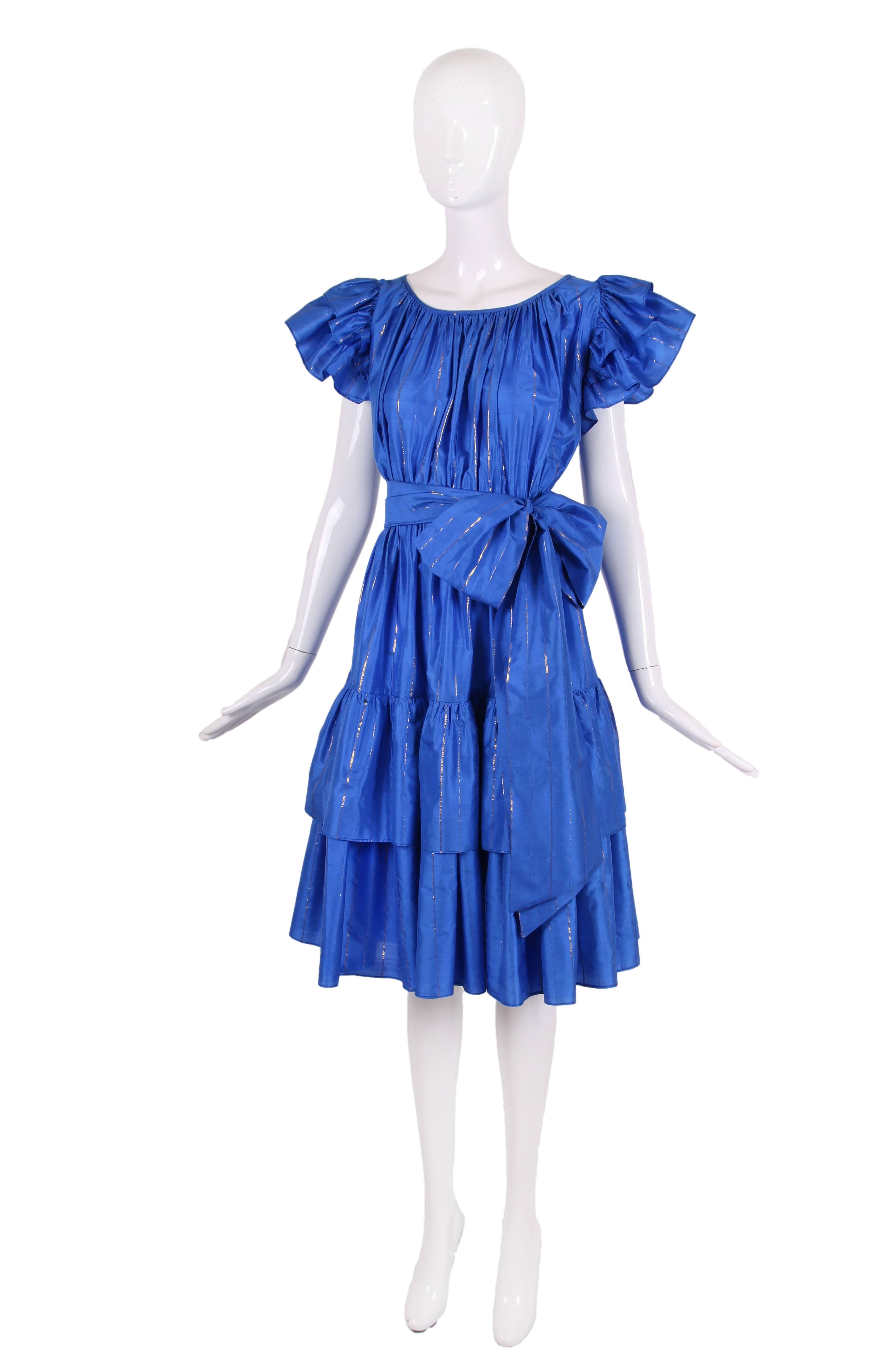 Vintage Yves Saint Laurent silk party dress in cobalt blue silk w/gold-ish metallic stripes. Features ruffled short sleeves and a tiered skirt. Comes with long self sash. In overall excellent condition with several very hard to see, small dark marks