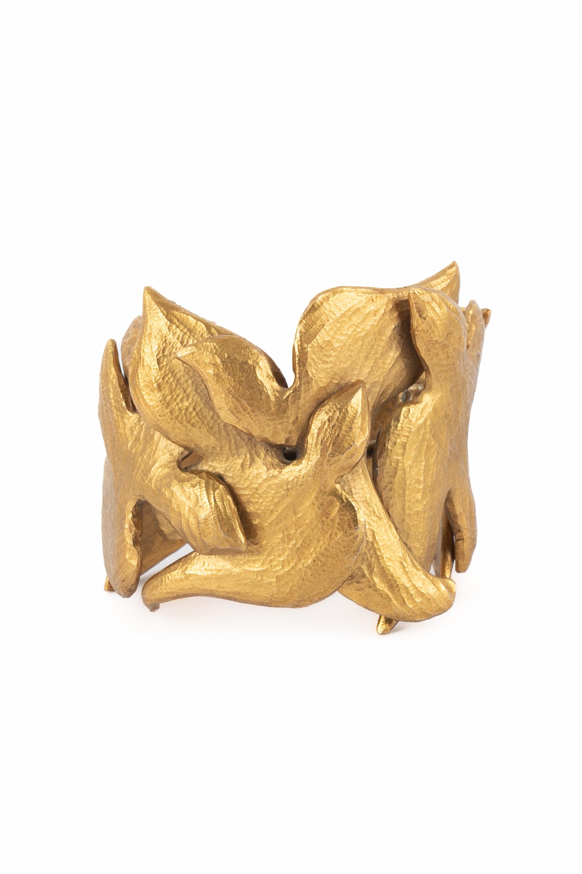 YVES SAINT LAURENT - Exceptionnel bracelet manchette en métal doré à motif de colombe. Non signé. Oeuvre de l'Atelier Robert Goossens. Collection Haute Couture printemps-été 1988.

Condit :
Très bon état.

Dimensions :
Longueur : 15 cm - Ouverture :